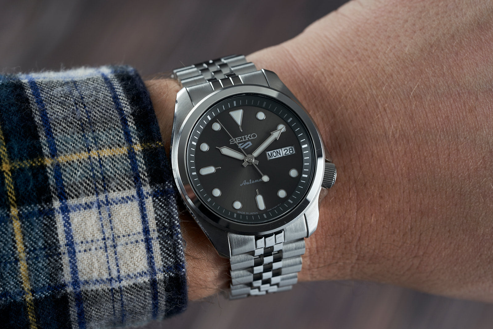 Seiko 5 automatic stainless steel watch with black dial and day-date window on jubilee bracelet, worn on wrist