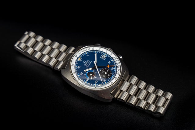 Omega Seamaster 176.007 chronograph watch with blue dial, steel bracelet, and orange accents on black background