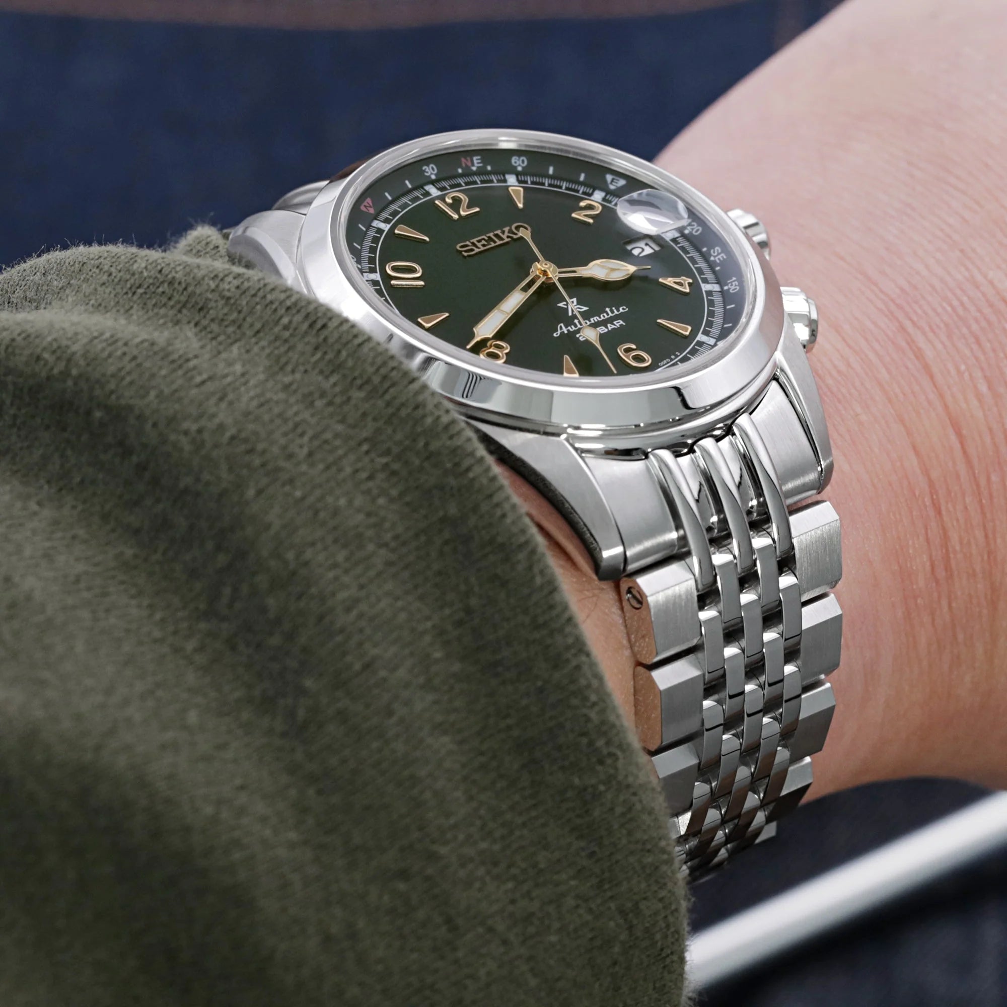 Seiko Alpinist SARB017 automatic watch with dark green dial, gold indices, stainless steel jubilee bracelet worn on wrist