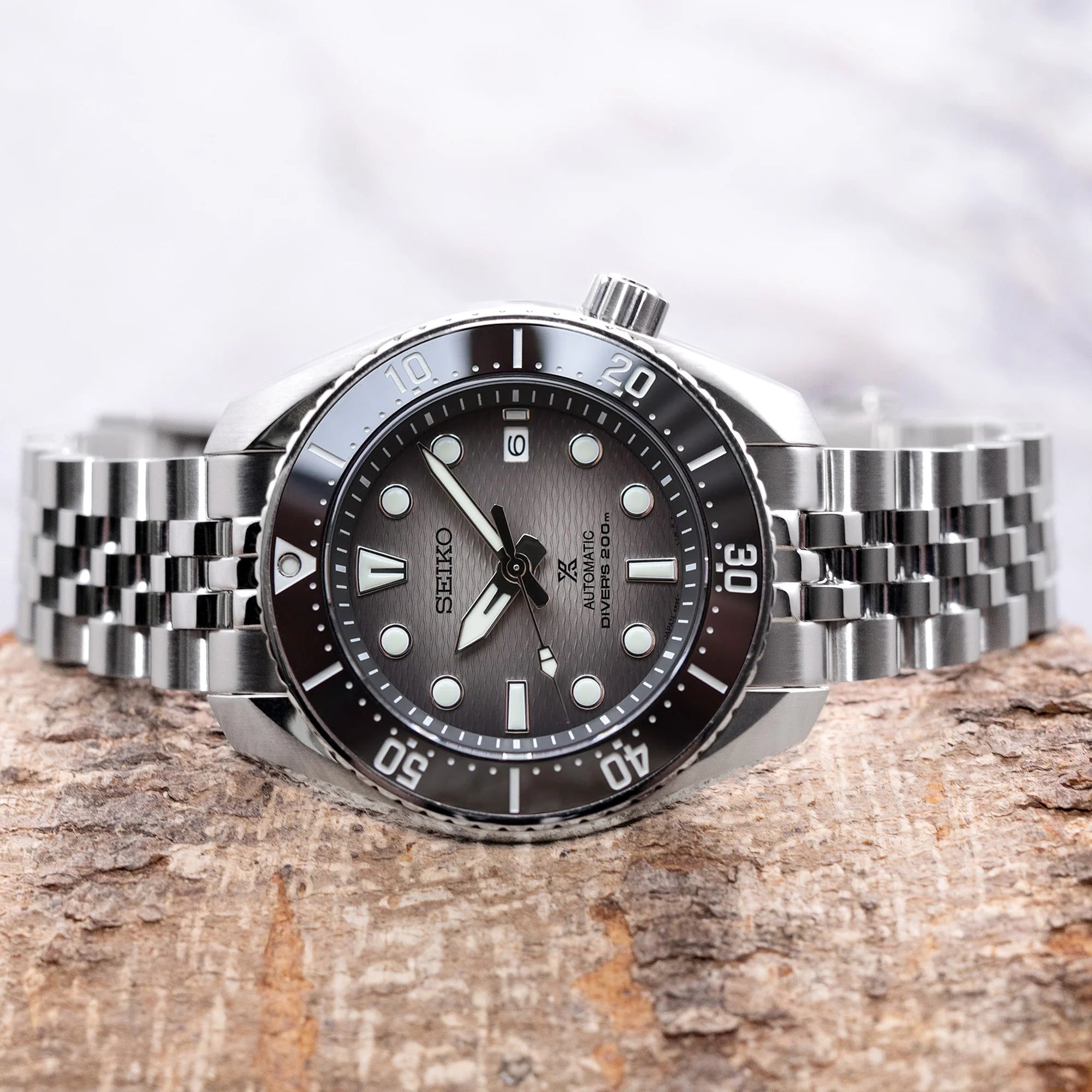 Stainless steel Angus-J Louis bracelet fitted on Seiko Sumo dive watch with black dial and rotating bezel on textured surface