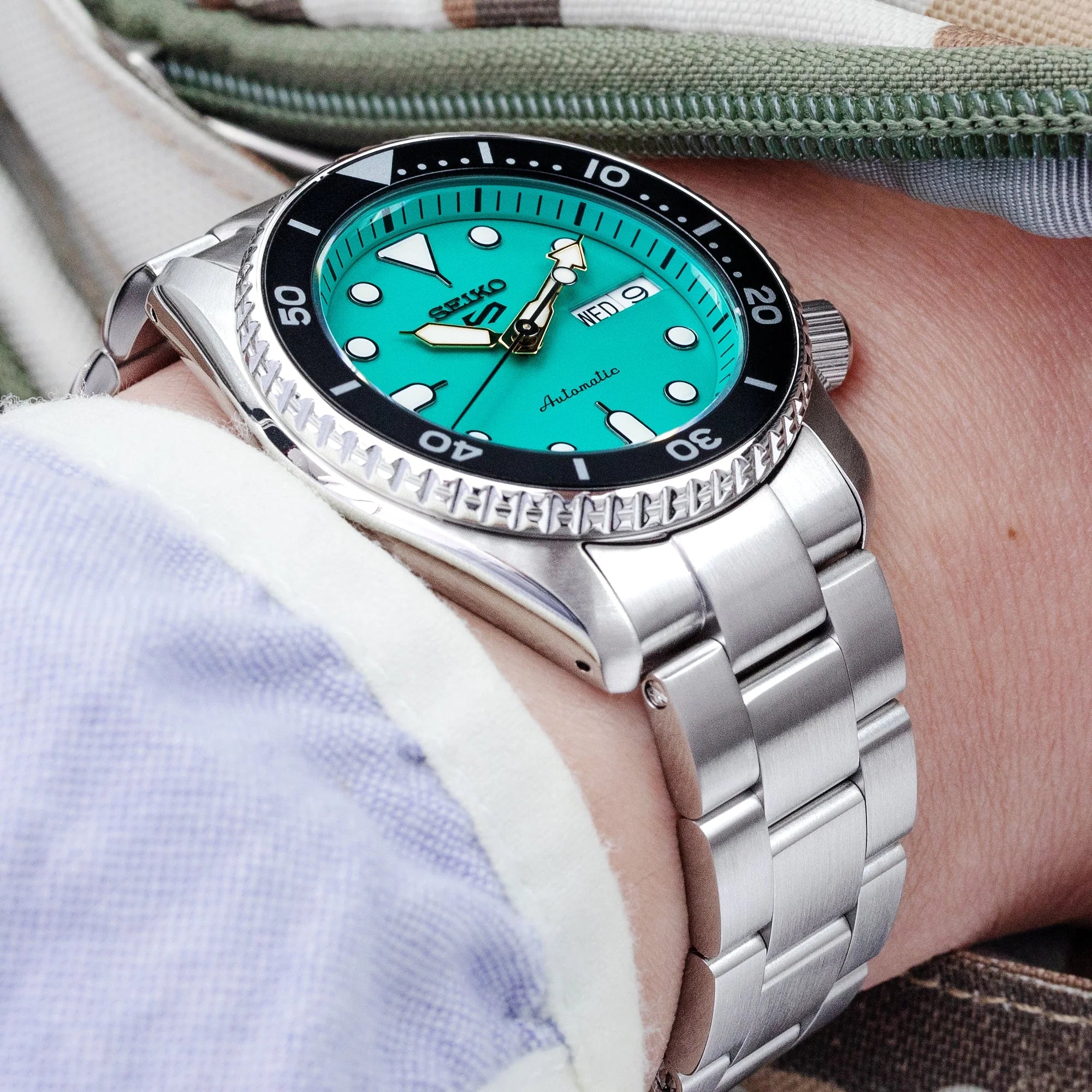 Seiko 5 Sports automatic watch with turquoise dial and stainless steel Super Boyer bracelet on wrist