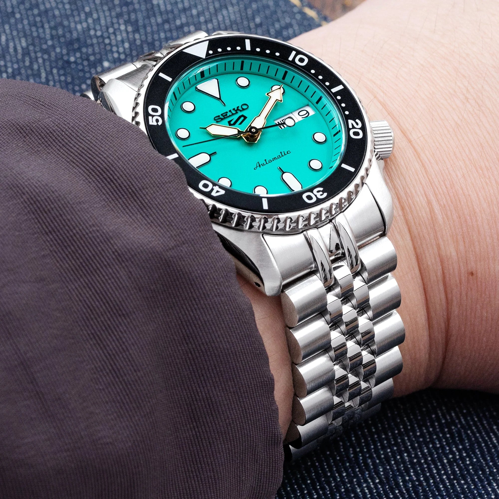 Seiko 5 Sports 38mm turquoise dial automatic watch with stainless steel Super-J Louis bracelet on wrist