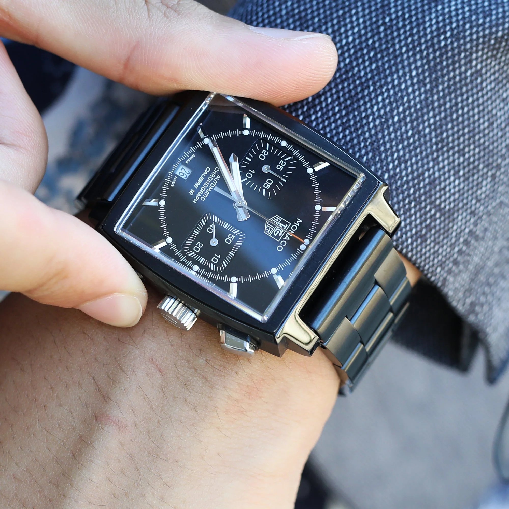 Black rectangular chronograph watch with dual subdials and steel bracelet, displayed on wrist