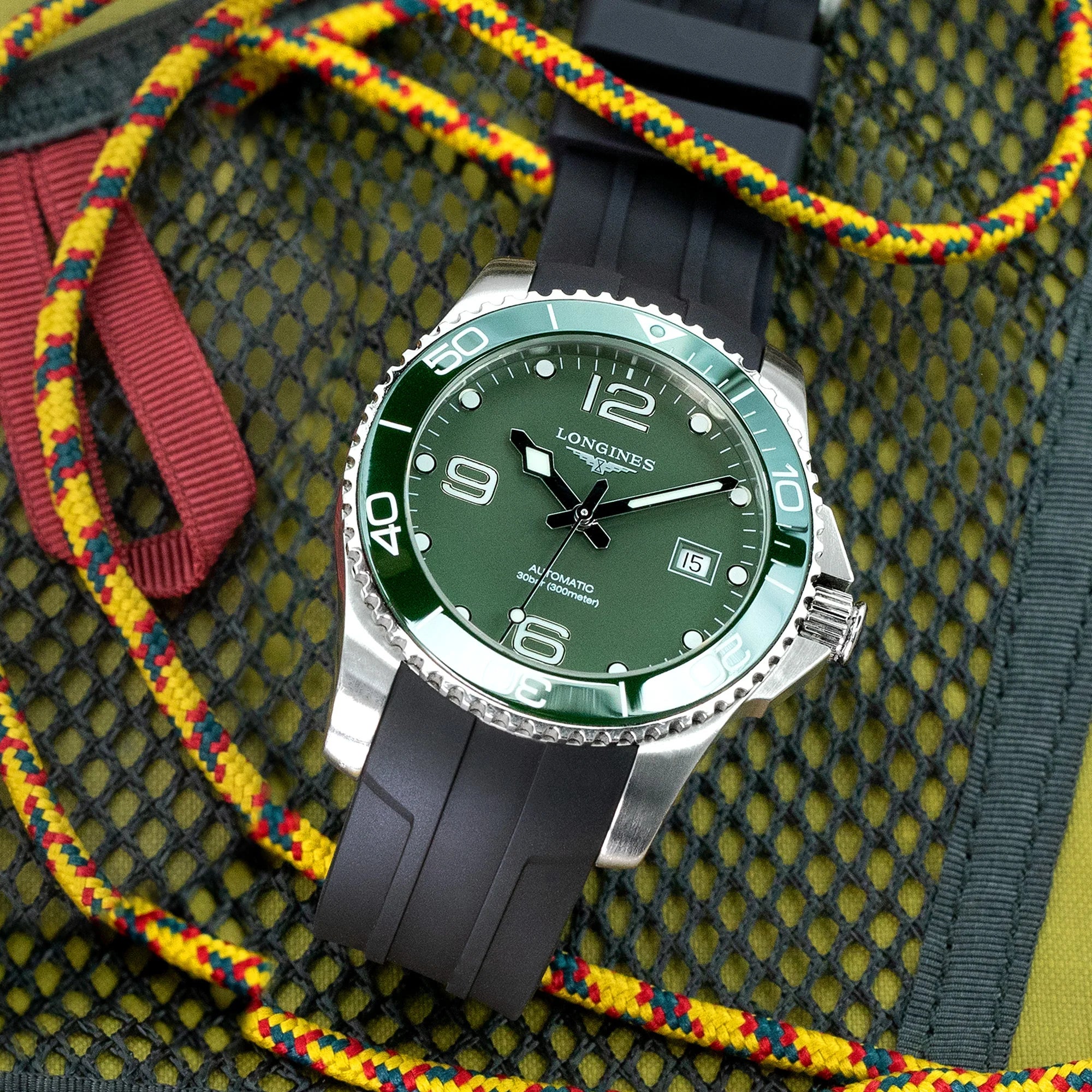 Longines HydroConquest watch with green dial, silver case, black rubber strap on colorful fabric background
