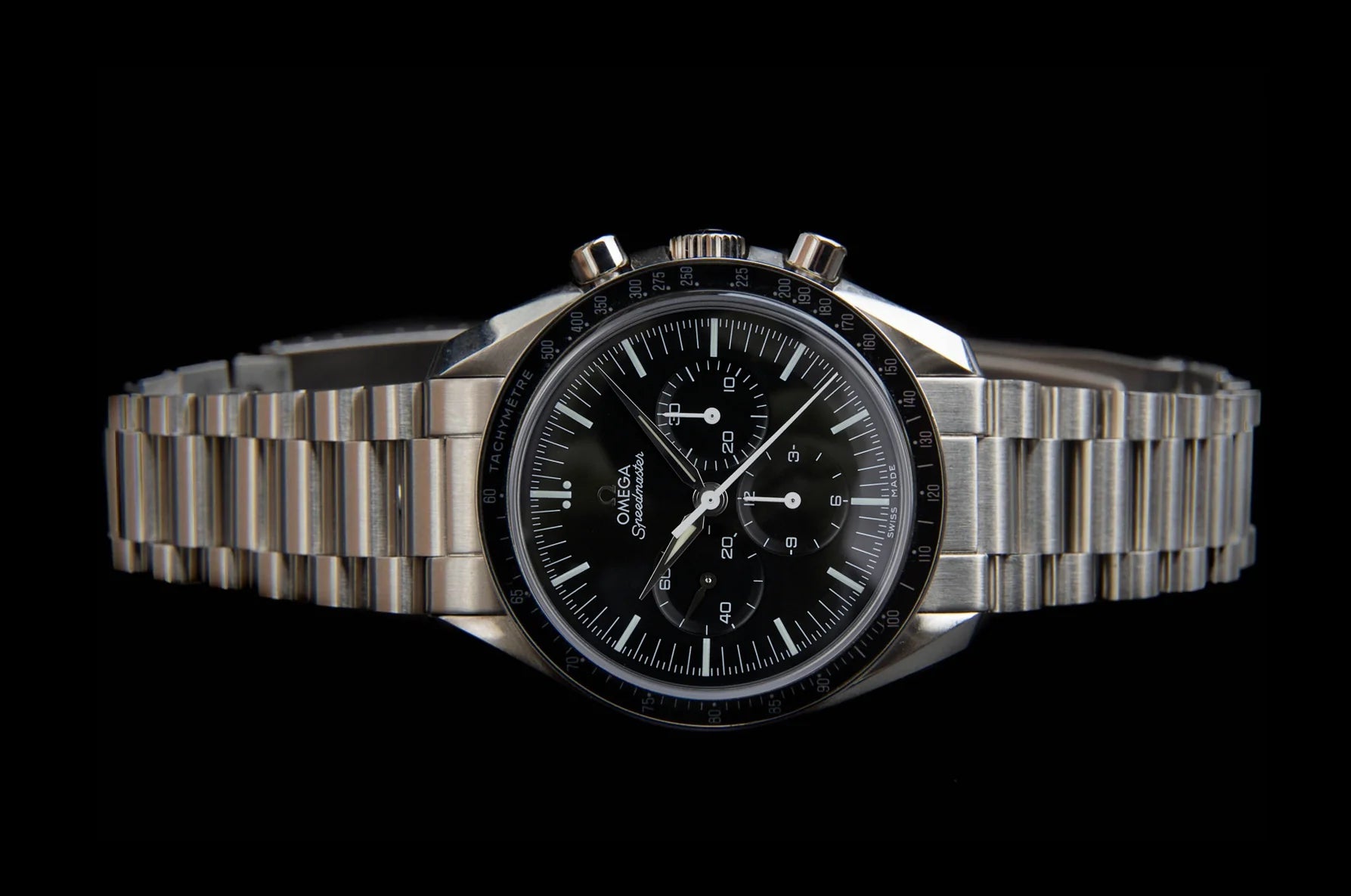 Omega Speedmaster Professional chronograph watch with black dial, stainless steel bracelet, and tachymeter bezel on black background