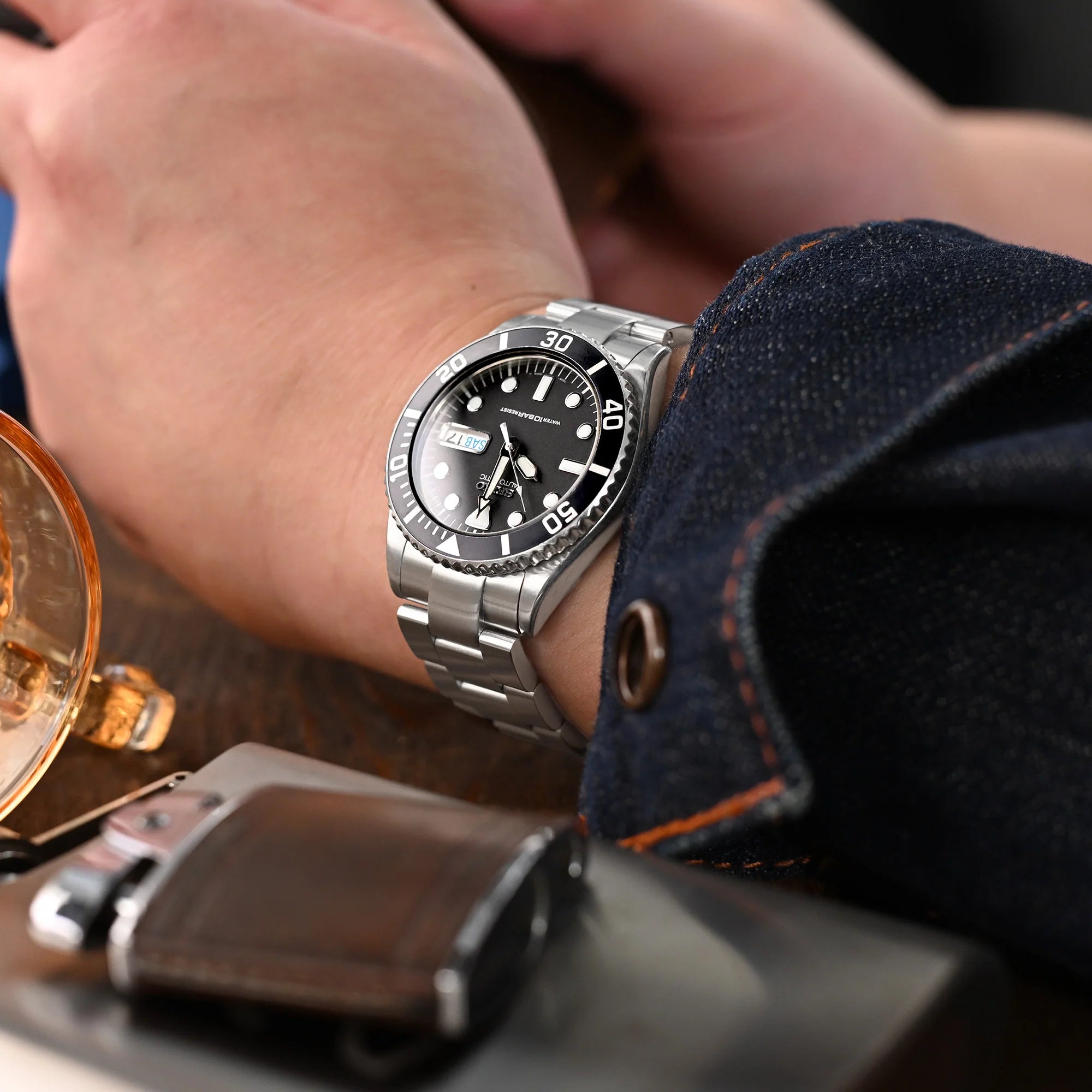 Strapcode Super-O Boyer bracelet on Seiko SKX023 dive watch with black dial worn on wrist with denim and accessories