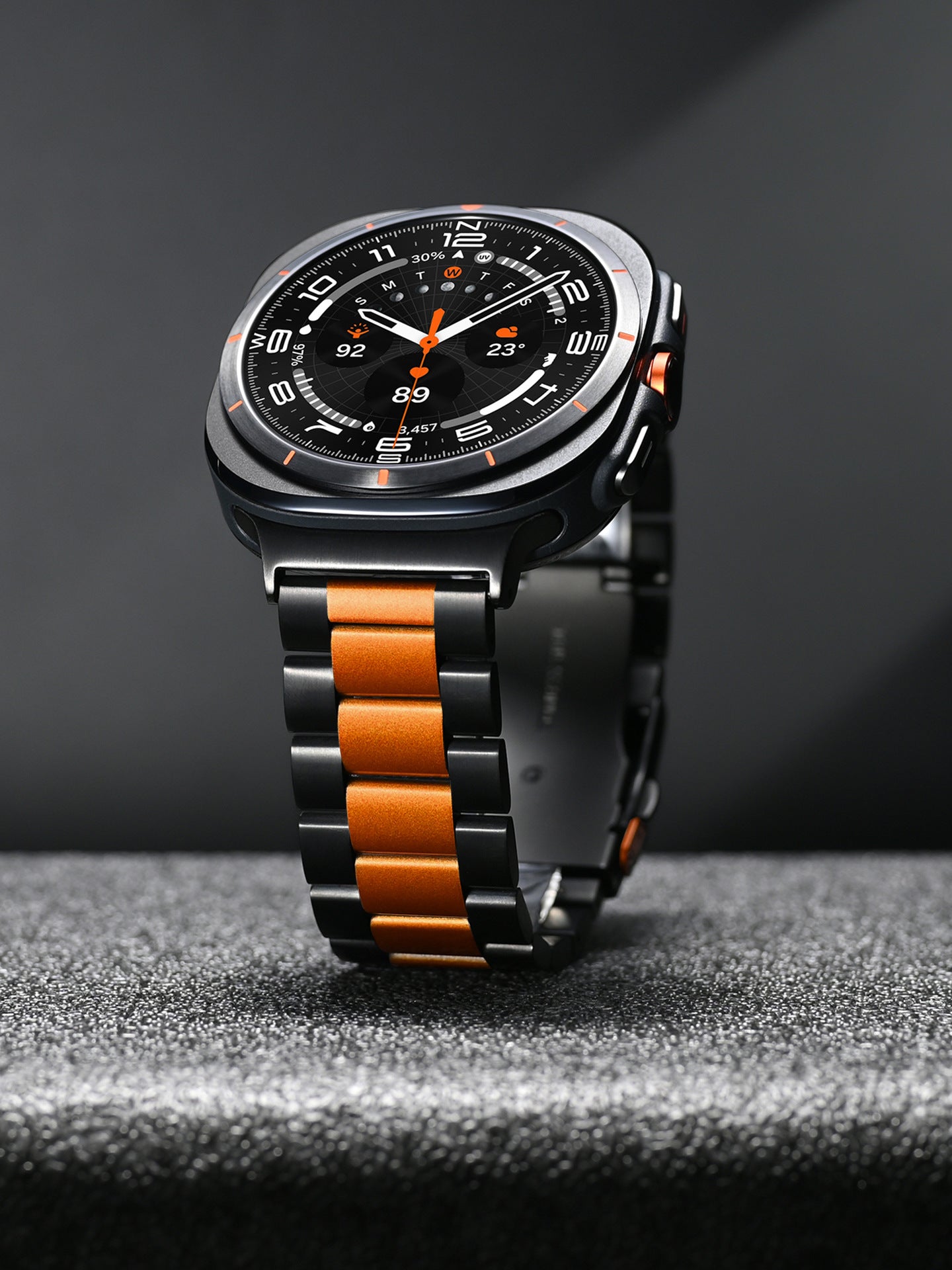 Black and orange stainless steel smartwatch with round dial, chronograph subdials, orange accents, and two-tone metal bracelet
