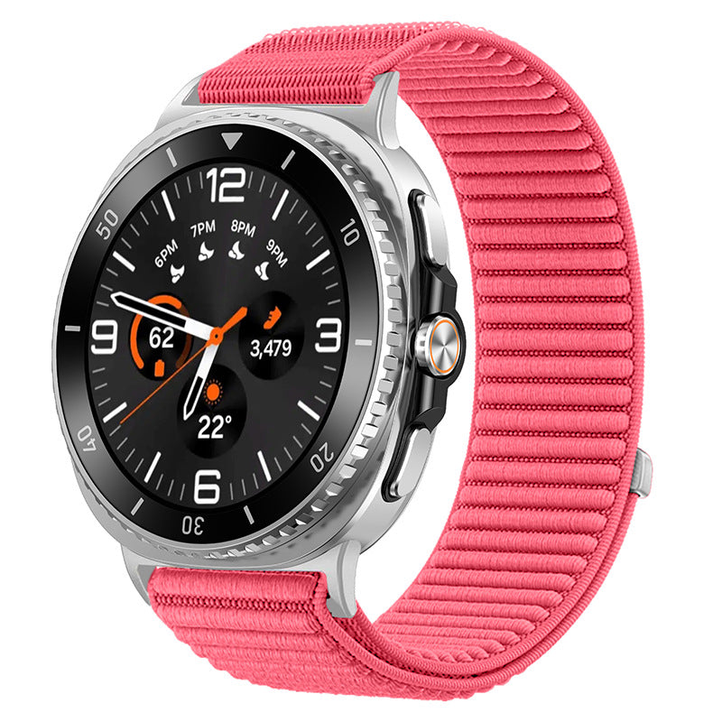 Silver smartwatch with black dial, orange accents, and pink sports loop band displaying time and fitness metrics