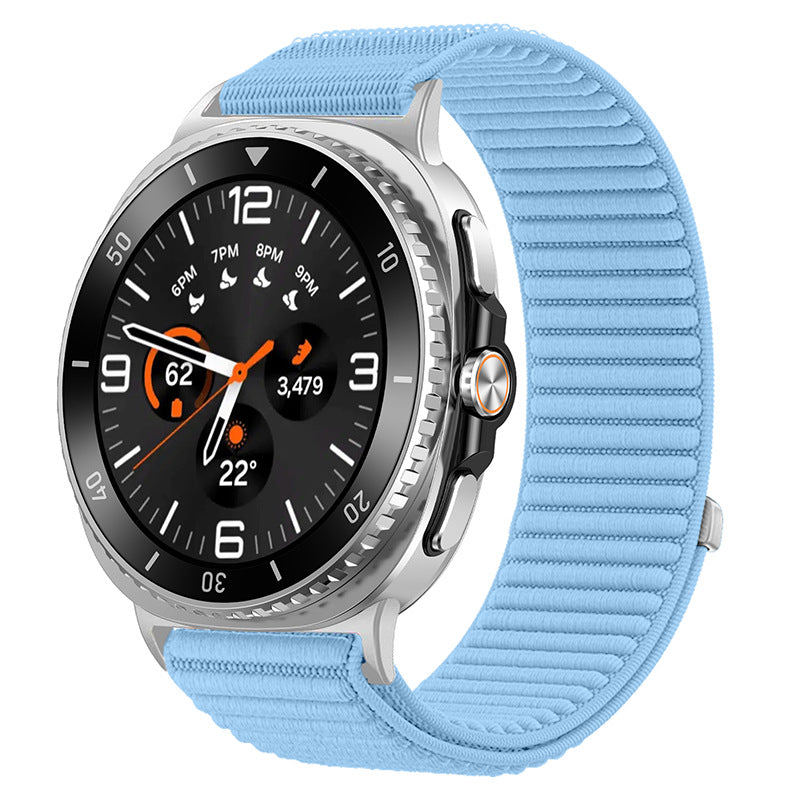 Silver smartwatch with black dial, orange accents, and light blue sports loop band displaying time and fitness metrics