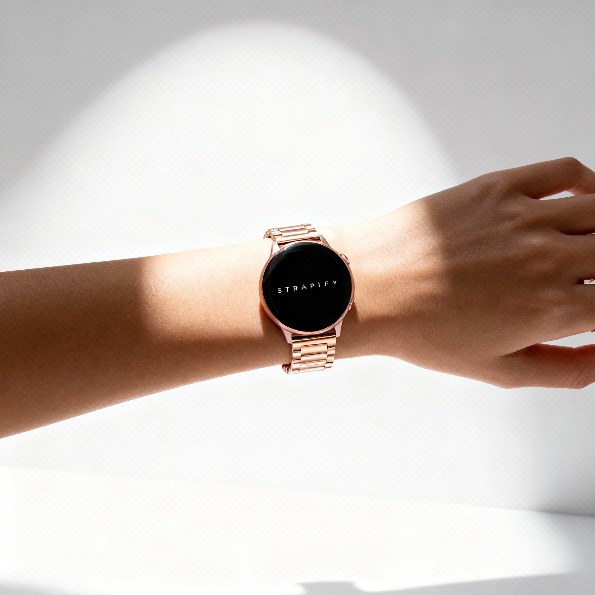 Rose gold stainless steel smartwatch with quick release bracelet and deployant clasp on woman's wrist