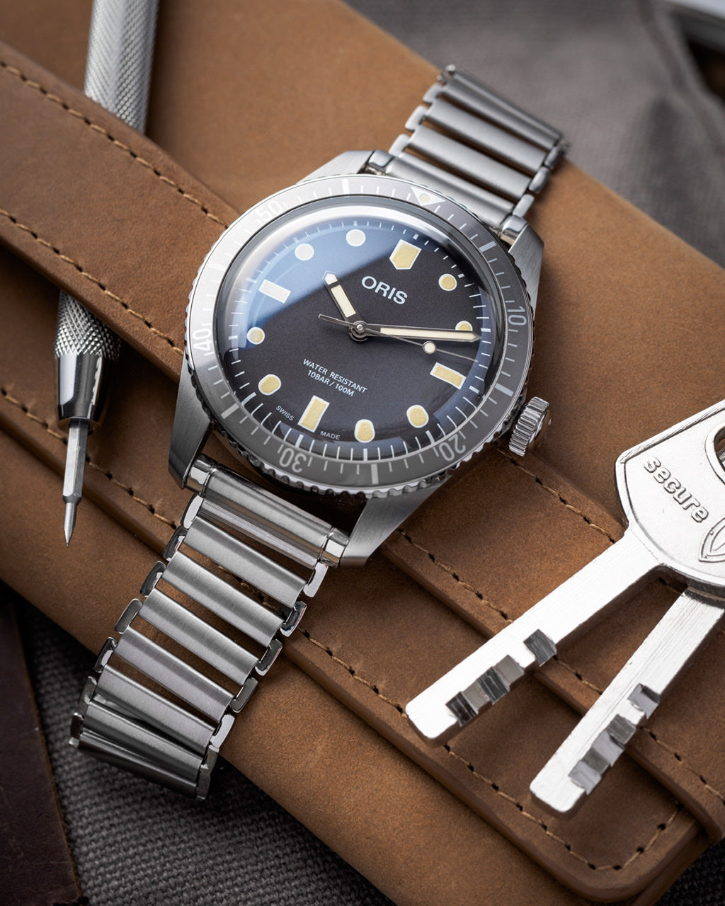 Oris stainless steel dive watch with black dial and luminous hour markers on brown leather strap display