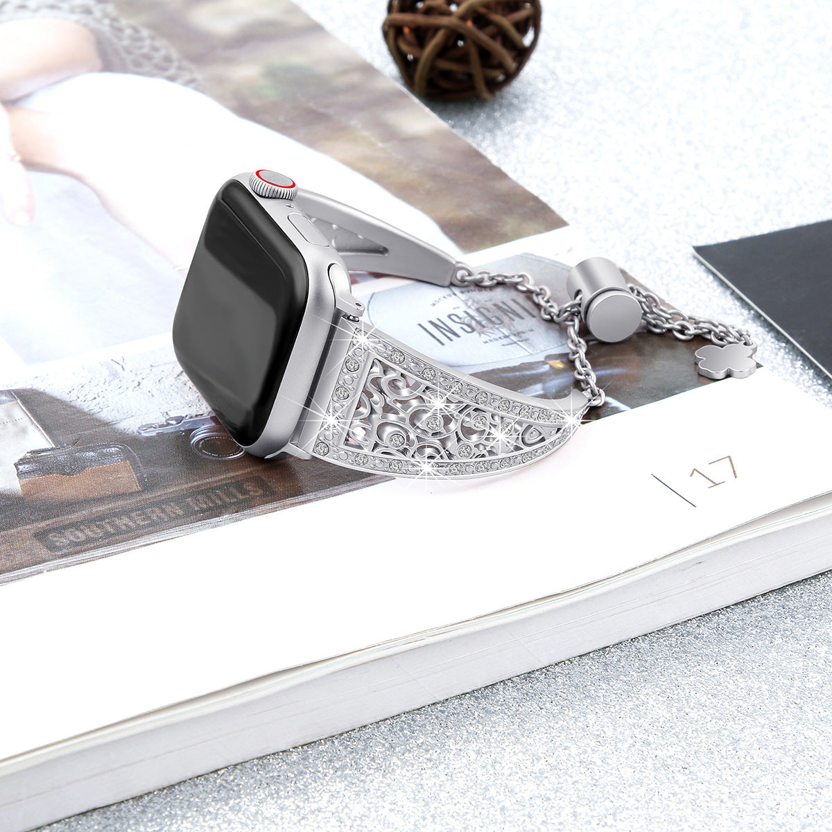 Silver ornate beauty bracelet smartwatch band with decorative filigree design and chain charm detail displayed on magazine