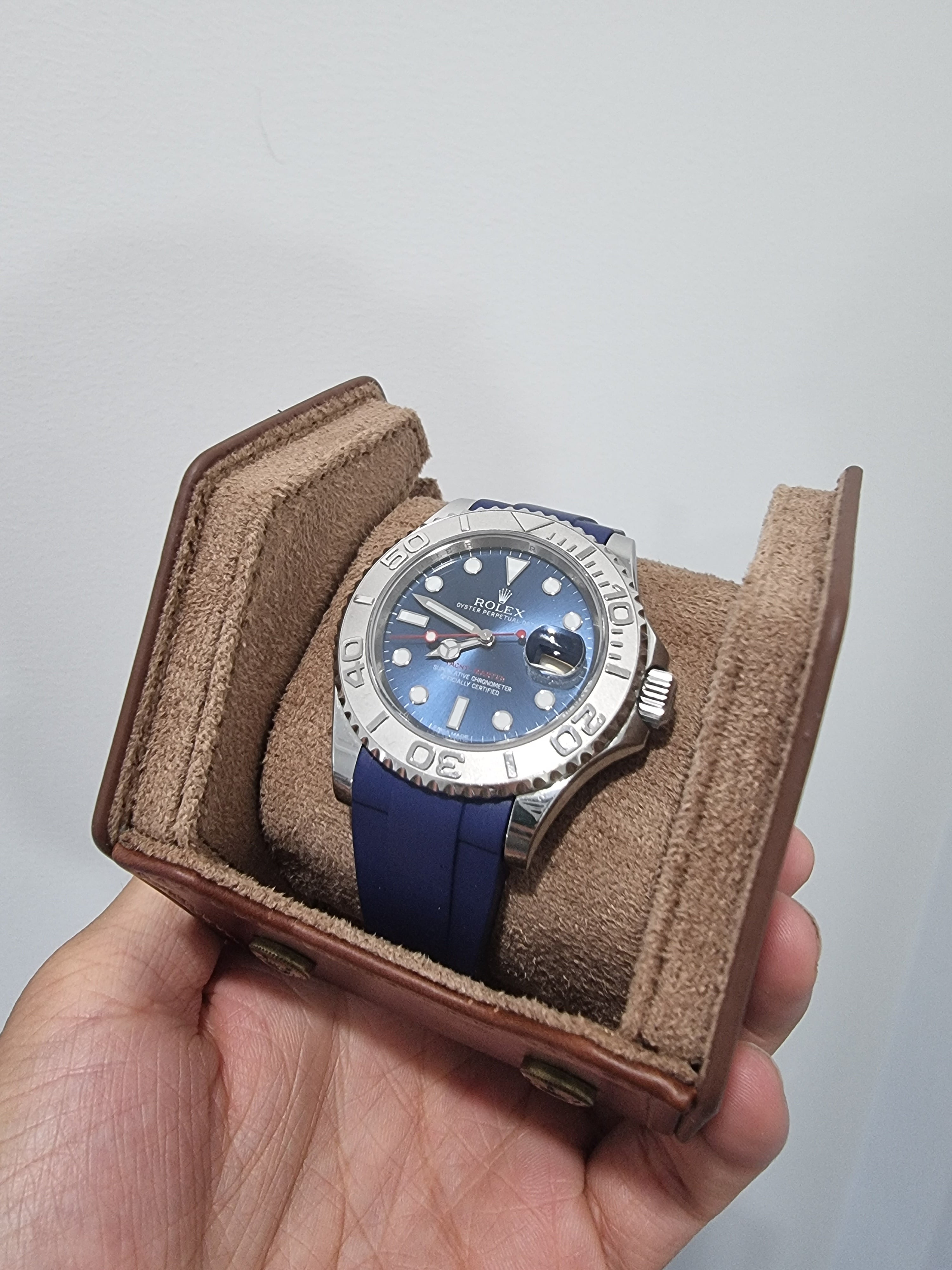 Luxury sport watch with stainless steel case and blue dial on navy rubber strap, displayed in brown leather presentation box