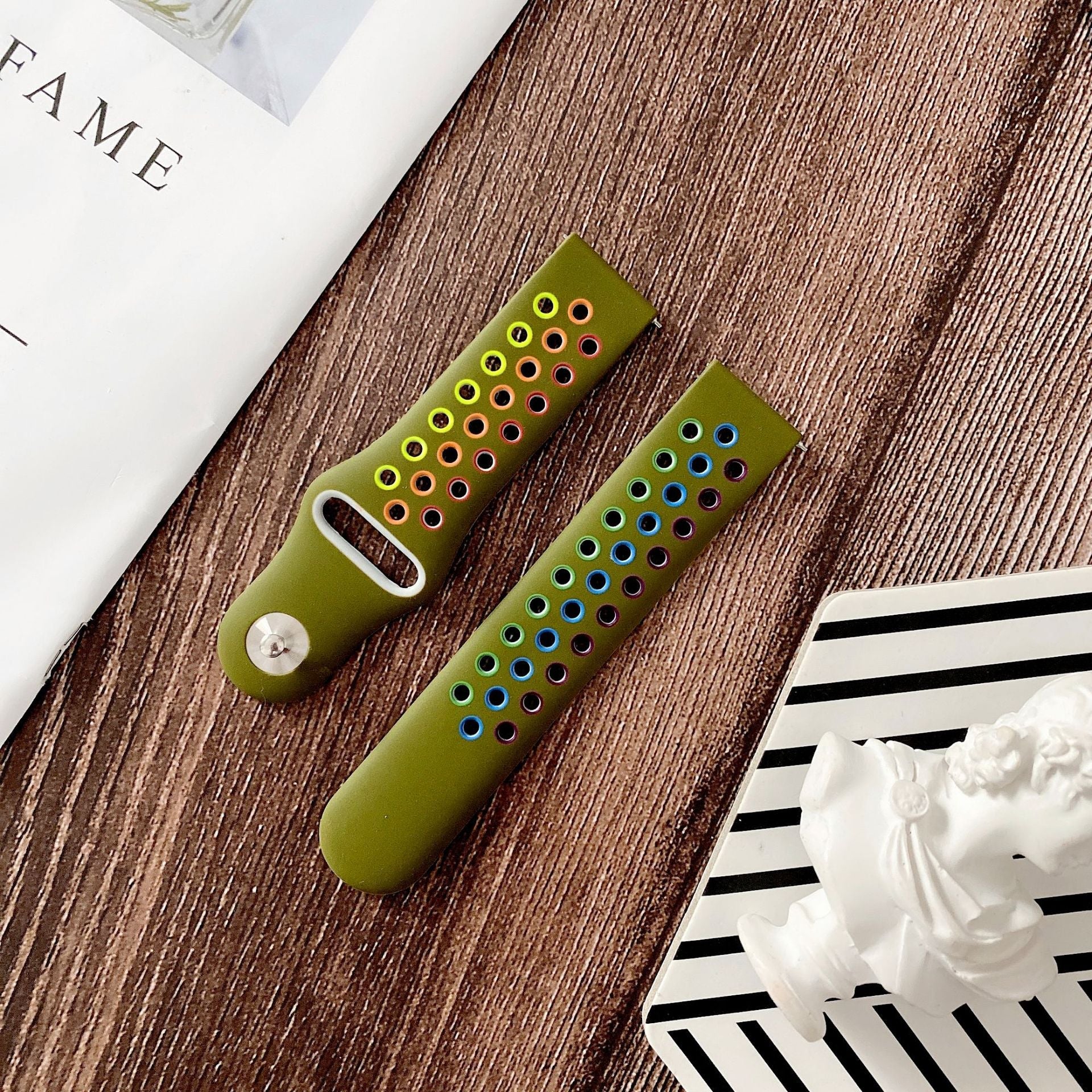 Olive green silicone sports watch band with colorful perforated holes and quick release mechanism displayed on wood surface