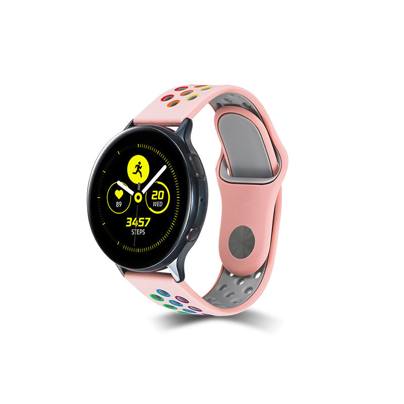 Pink silicone sports watch band with rainbow quick release dots, compatible with round smartwatch faces, featuring gray ventilation holes