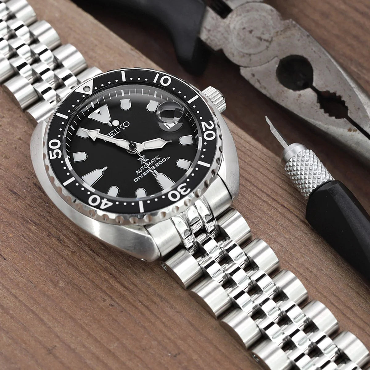 Seiko Mini Turtle dive watch with stainless steel Angus-J Louis bracelet on wooden surface with tools