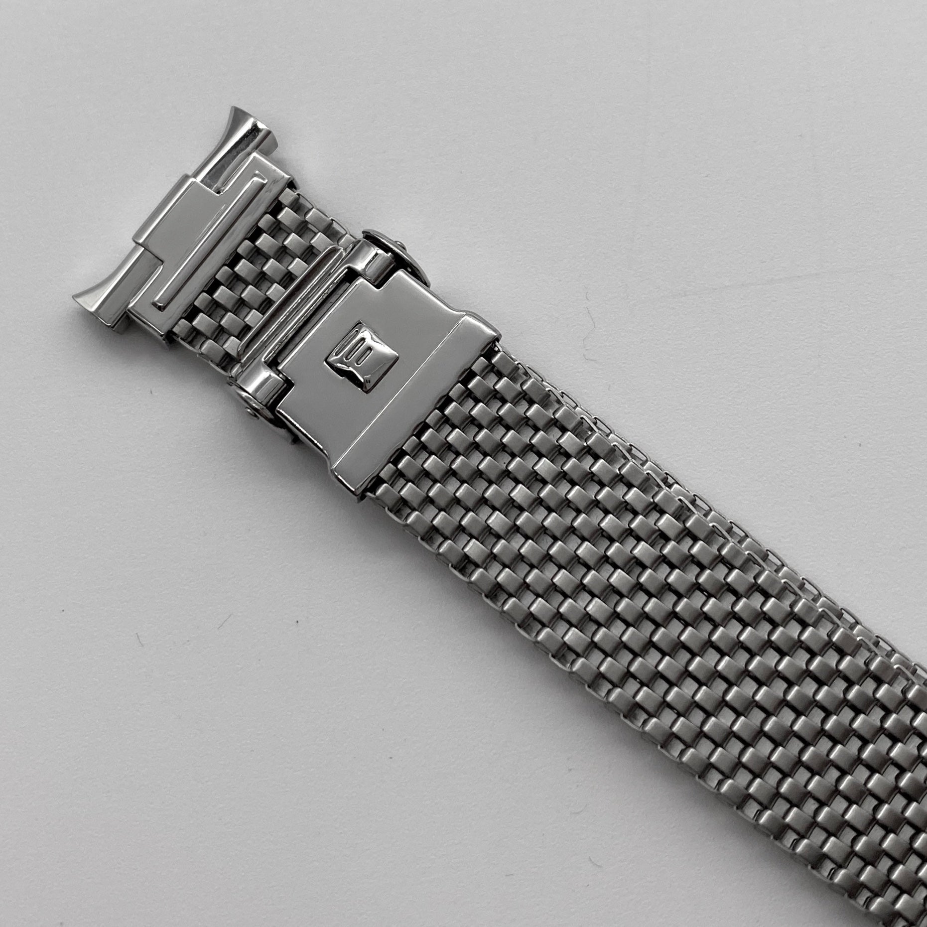 Stainless steel mesh watch bracelet with horned end lugs and fold-over clasp, top-down view