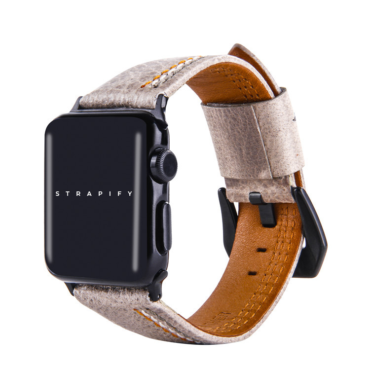 Ivory white leather Apple Watch band with asymmetrical tan stitching, tan leather interior, and black hardware connector