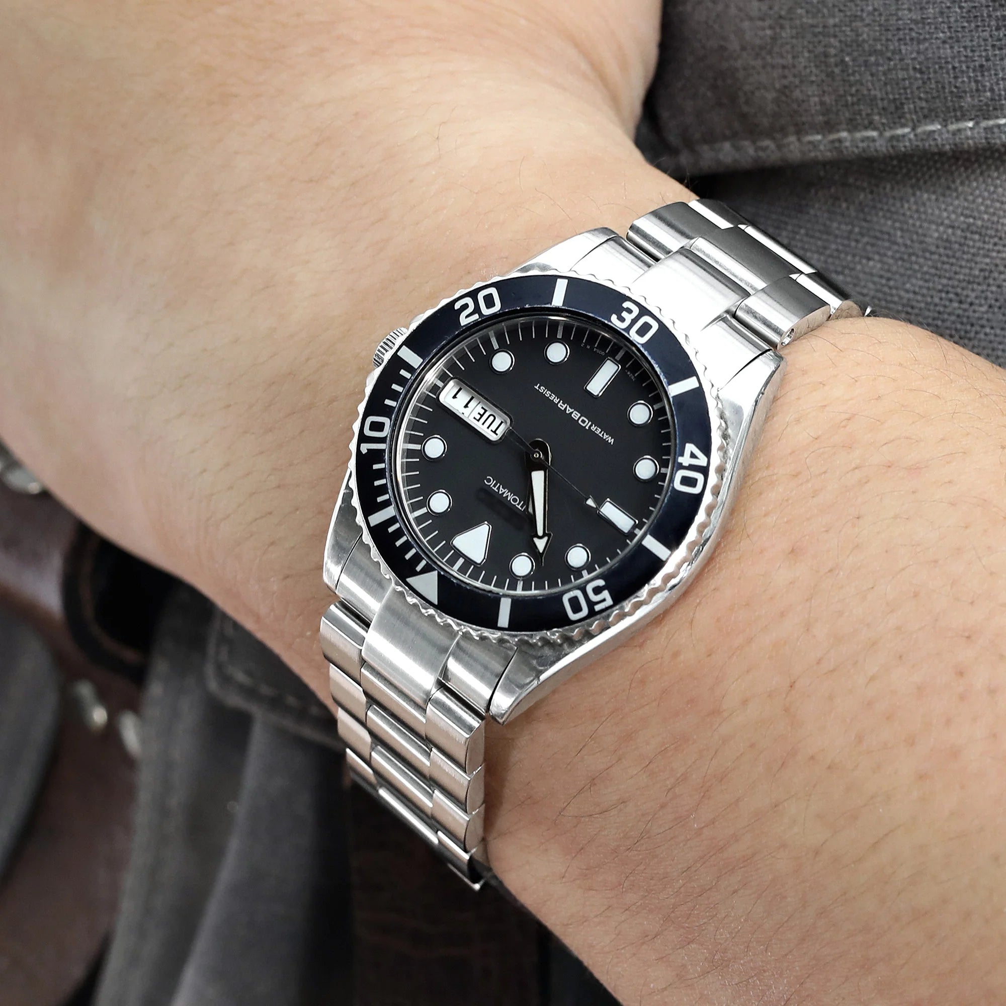 Men's stainless steel dive watch with black dial and rotating bezel on metal bracelet worn on wrist
