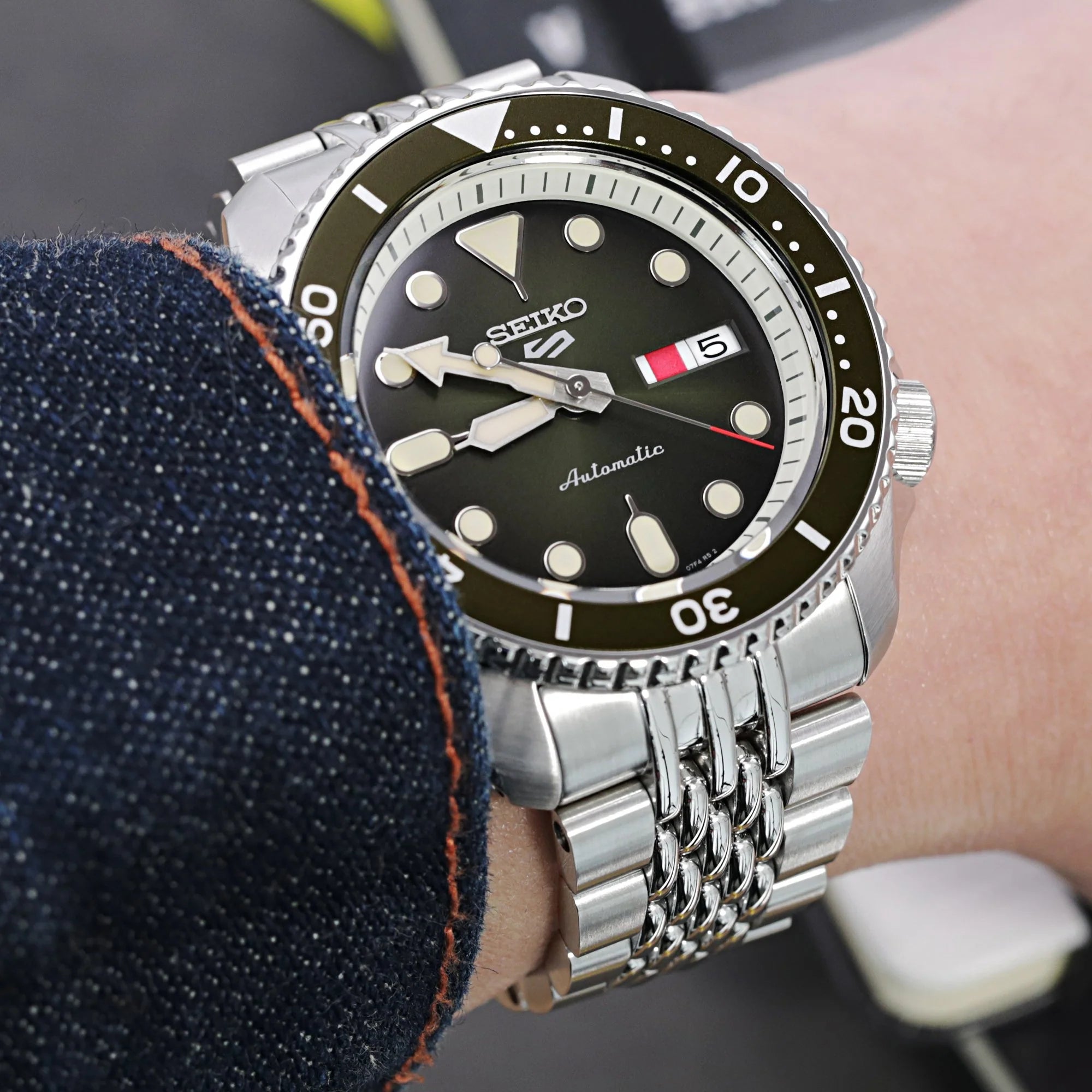 Seiko 5 automatic dive watch with black dial and steel bracelet worn on wrist