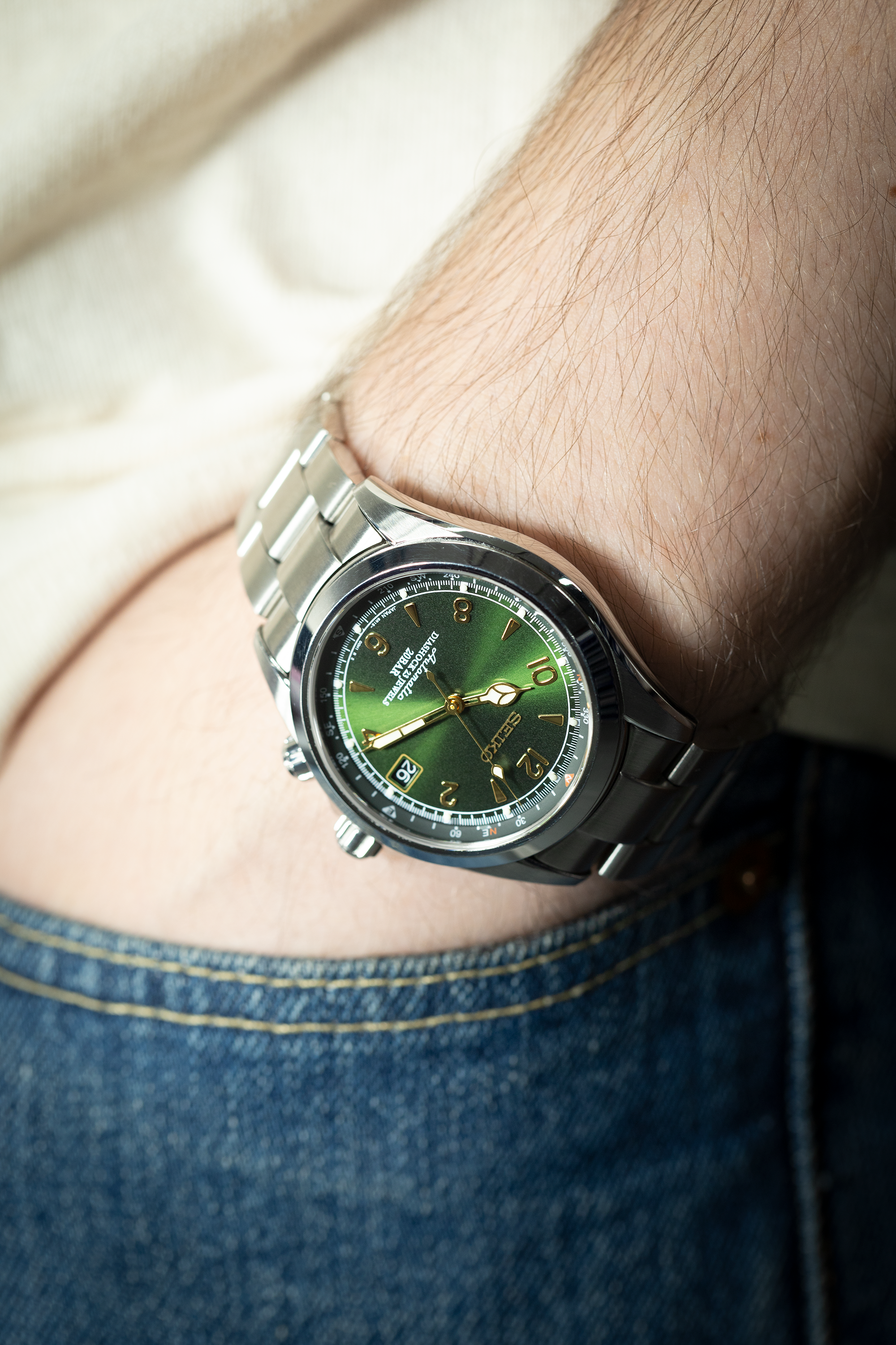 Seiko Alpinist watch with green dial and stainless steel bracelet worn on wrist, showcasing micro-adjustable clasp and gold accents