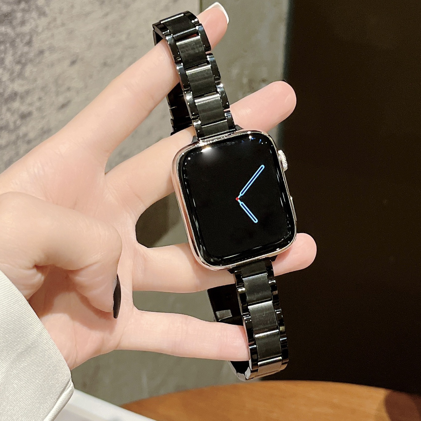 Black stainless steel smartwatch with rectangular display and matching metal link bracelet held in hand showing time display