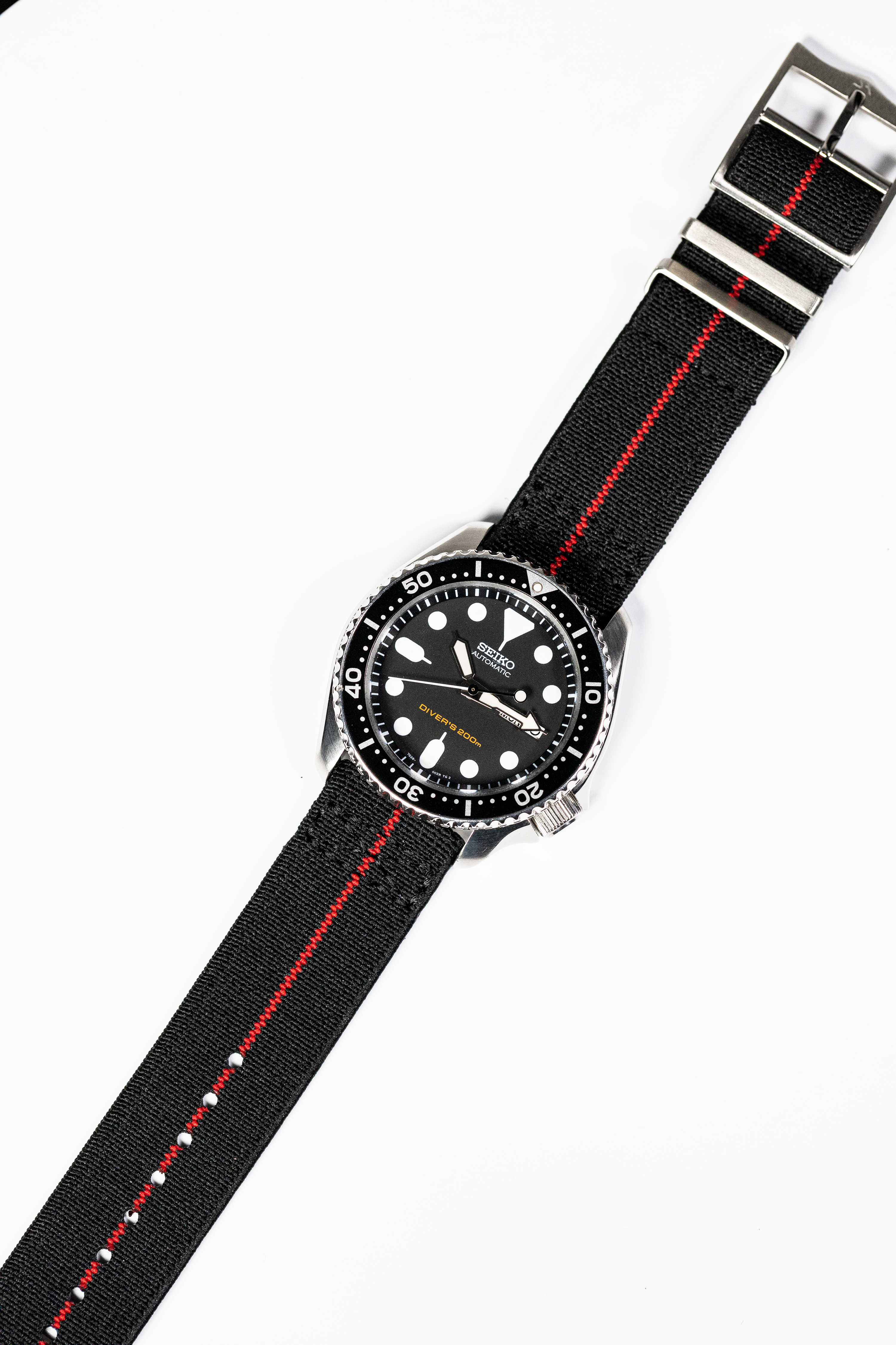 Seiko diver watch with black dial and rotating bezel on black fabric strap with red stripe and quick release buckle