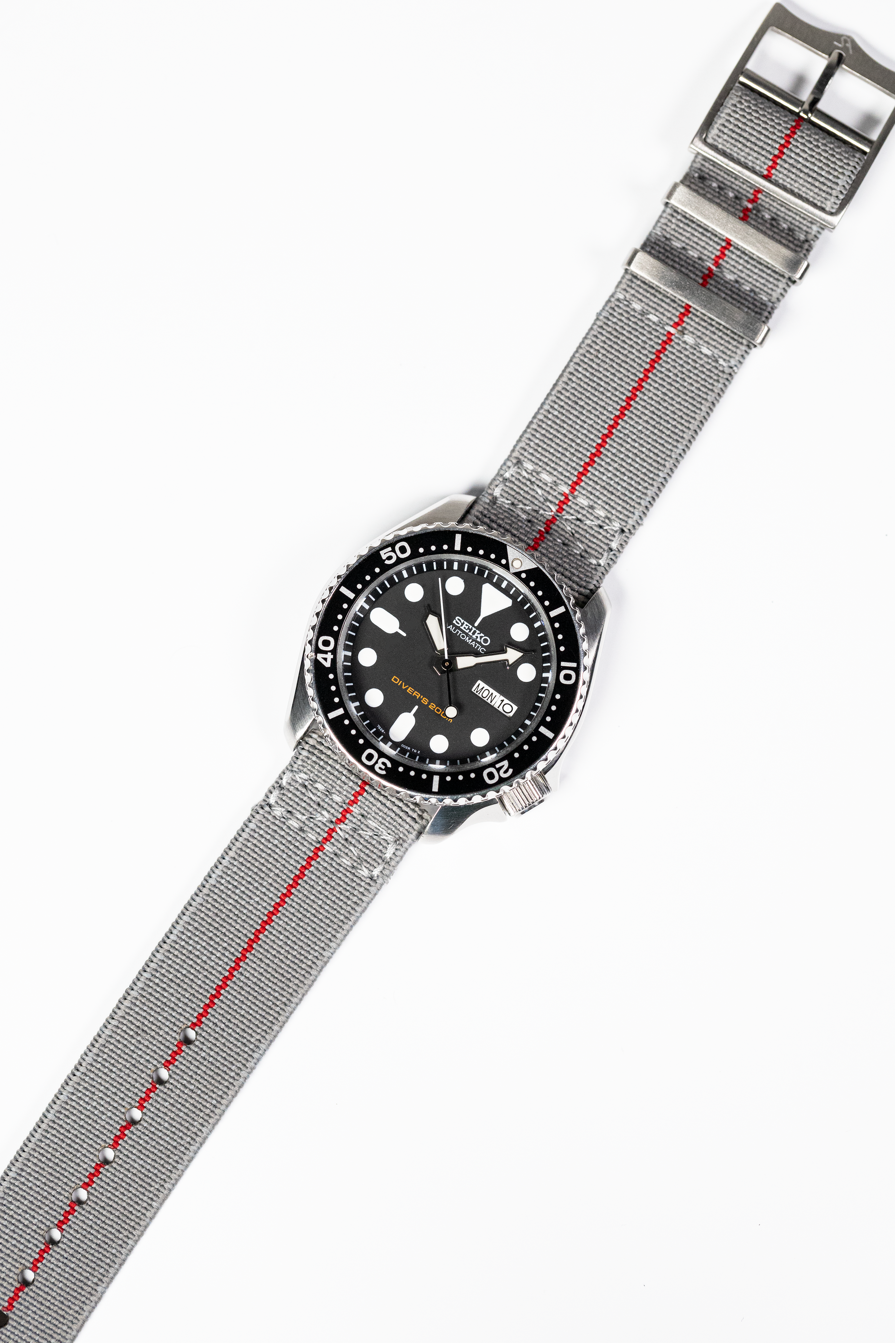 Seiko diver watch with black dial and rotating bezel on gray fabric strap with red stripe and quick release buckle
