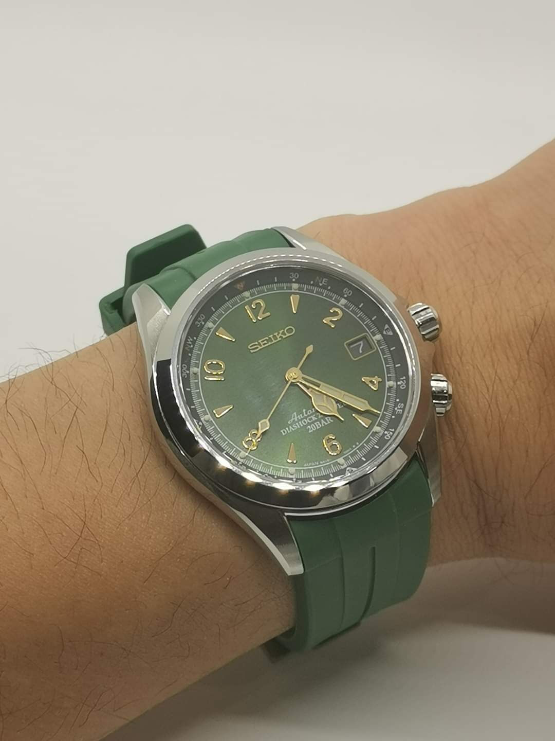 Seiko automatic watch with green dial and gold indices on green rubber strap, worn on wrist