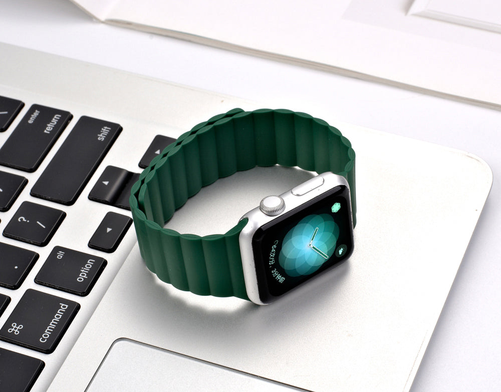 Green magnetic silicone loop band for smartwatch with silver case on laptop keyboard