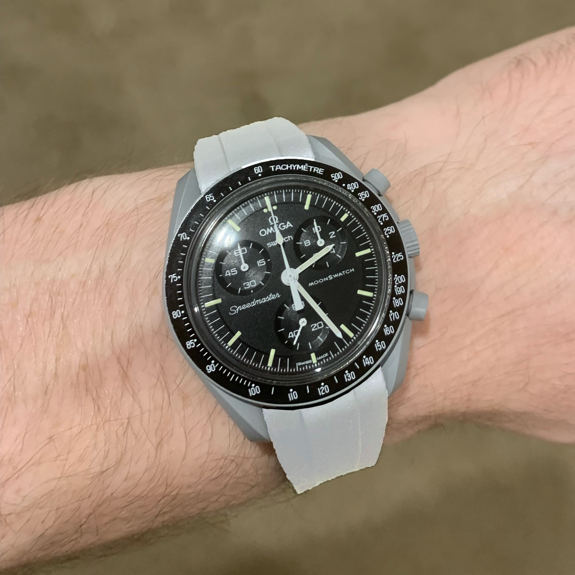 Omega Swatch MoonSwatch chronograph watch with black dial, white rubber strap, and tachymetre bezel on wrist