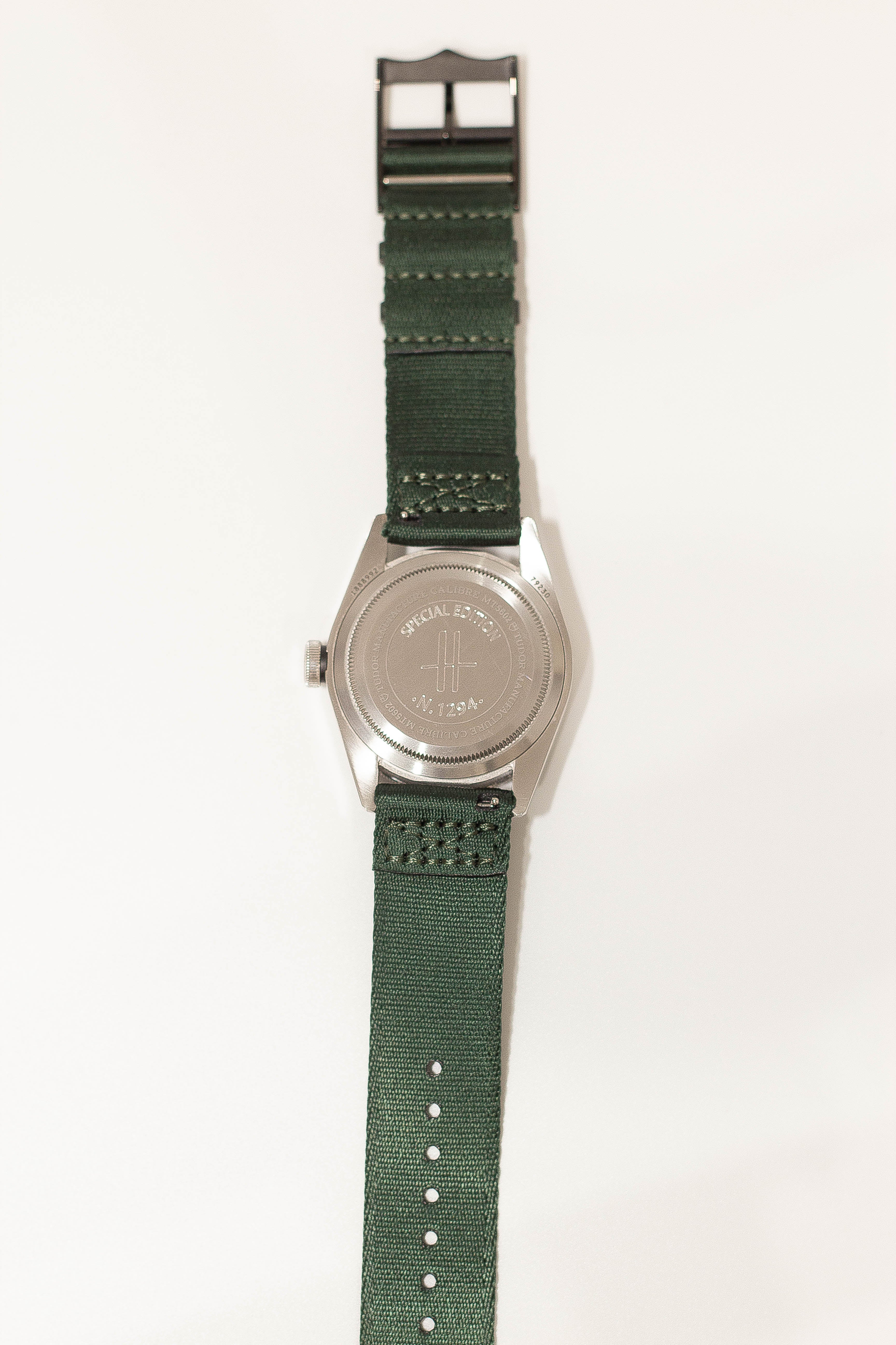 Special edition military watch with silver case, green canvas strap, white stitching and quick release black hardware