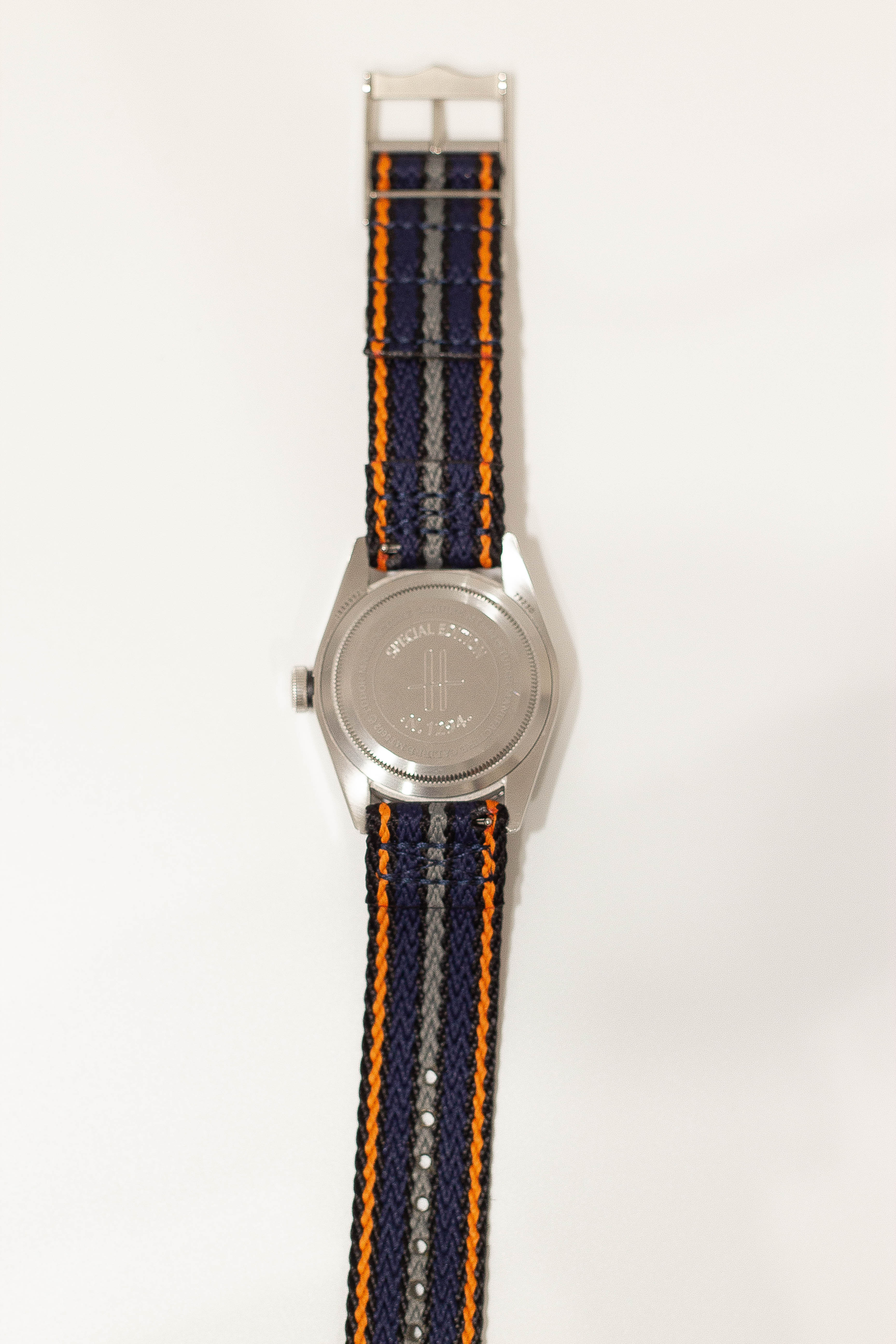 Stainless steel military watch with navy blue and orange striped fabric quick release strap and grey dial