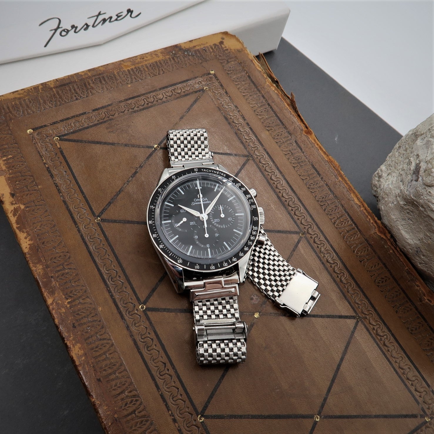 Stainless steel mesh watch bracelet with checkered pattern and horned ends on vintage leather journal