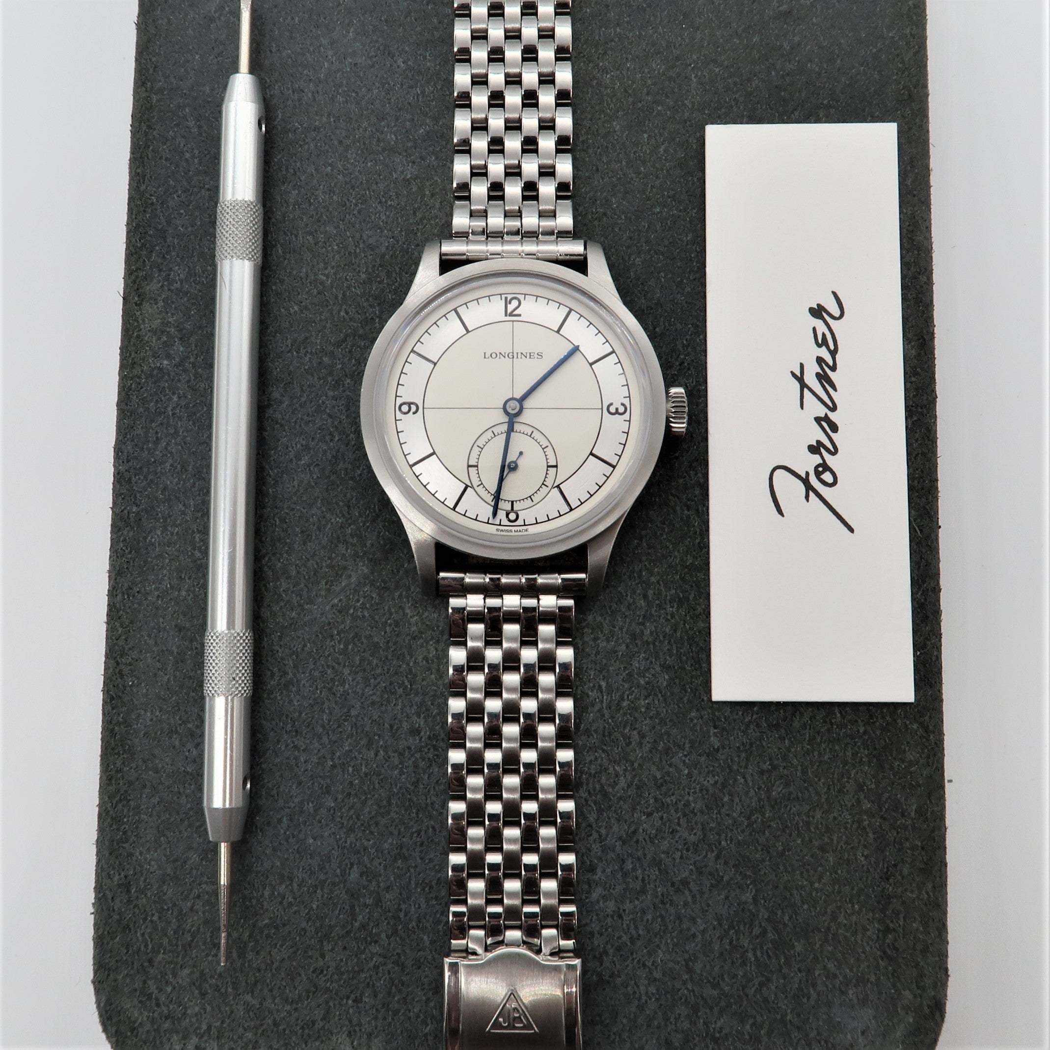 Longines stainless steel watch with silver bracelet and sub-dial on dark felt with spring bar tool and warranty card
