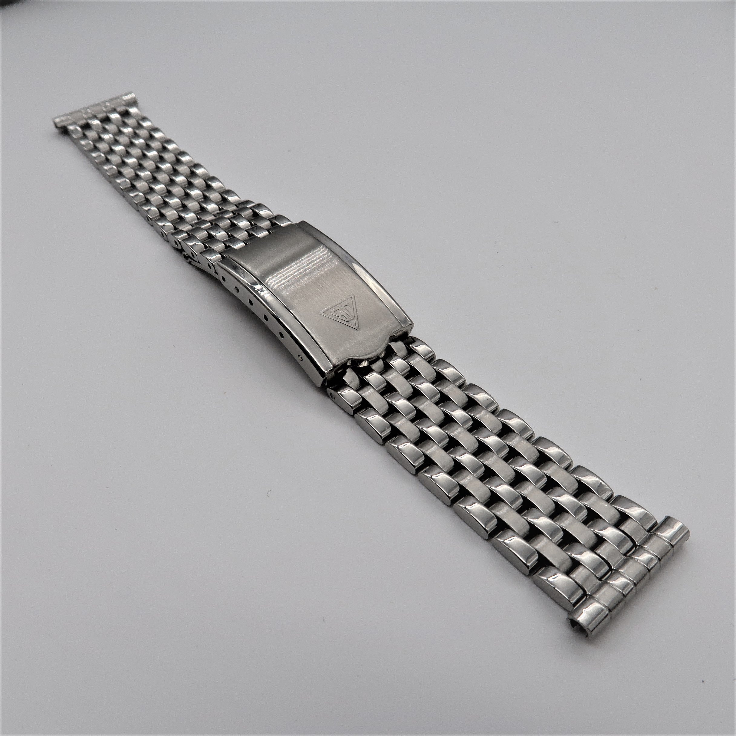 Forstner 7-row beads of rice stainless steel watch bracelet with polished end links and adjustable links on gray background