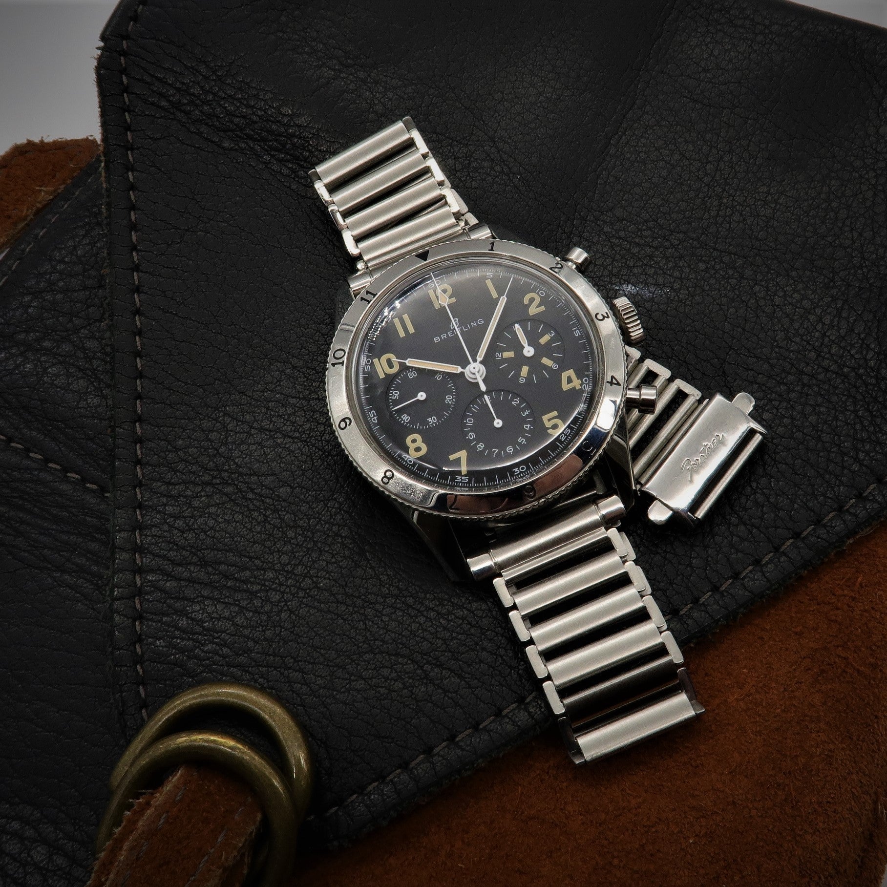 Stainless steel ladder-style watch bracelet with polished links displayed on luxury chronograph timepiece with black dial