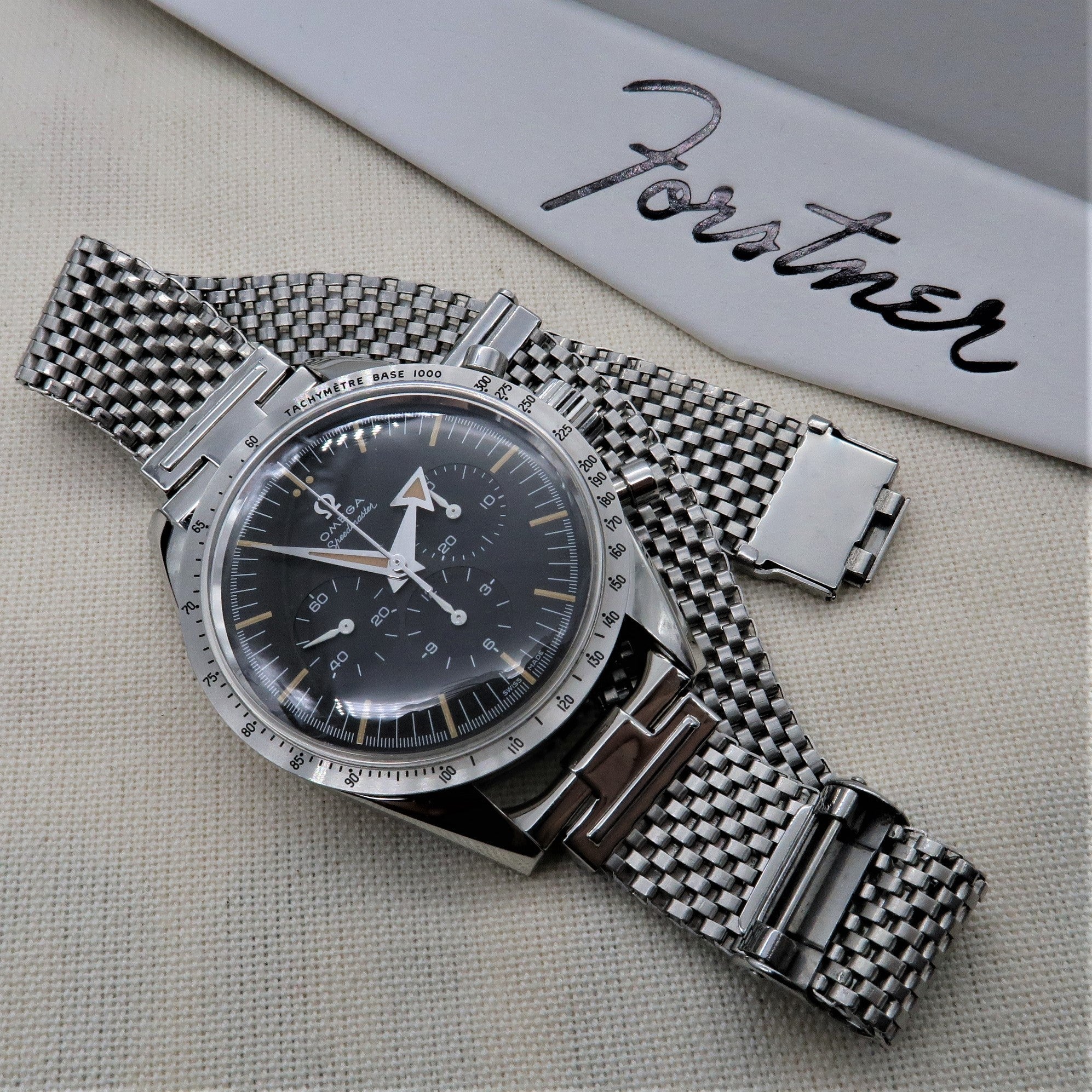 Vintage Omega chronograph watch with black dial and tachymetre bezel on stainless steel mesh bracelet