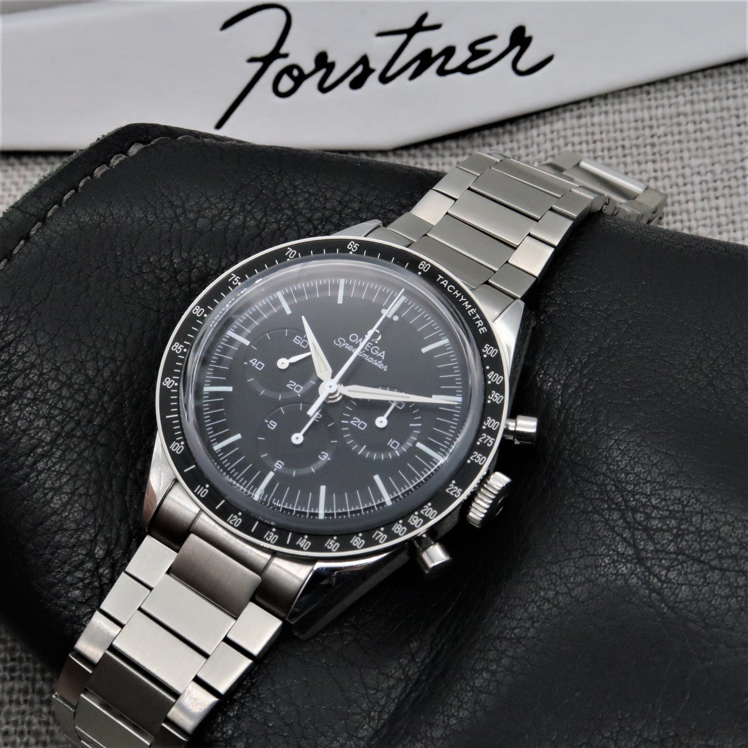 Omega Speedmaster professional chronograph watch with stainless steel flat link bracelet on black leather strap