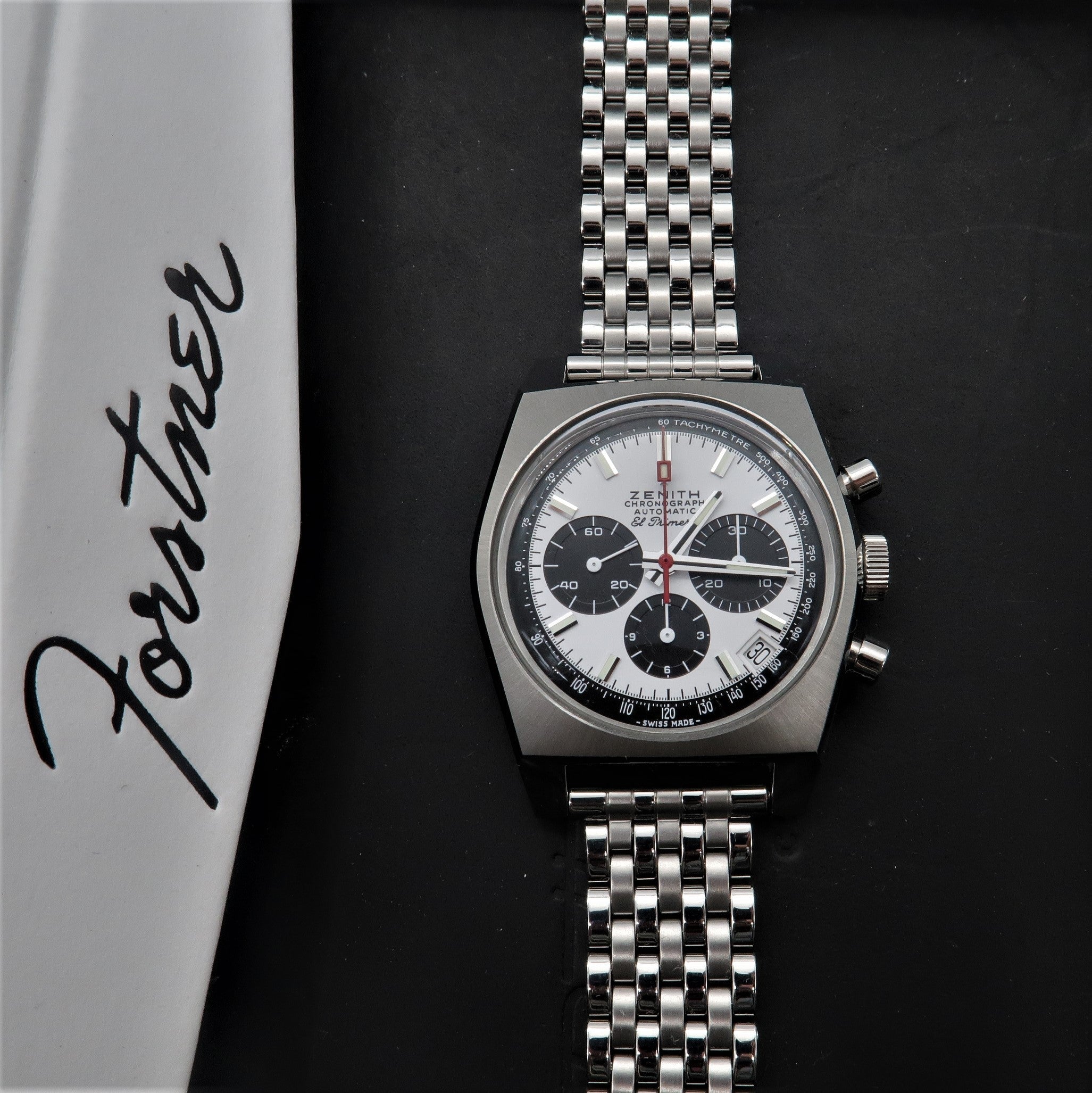 Zenith vintage chronograph watch with silver dial, black subdials, and stainless steel bracelet on black background