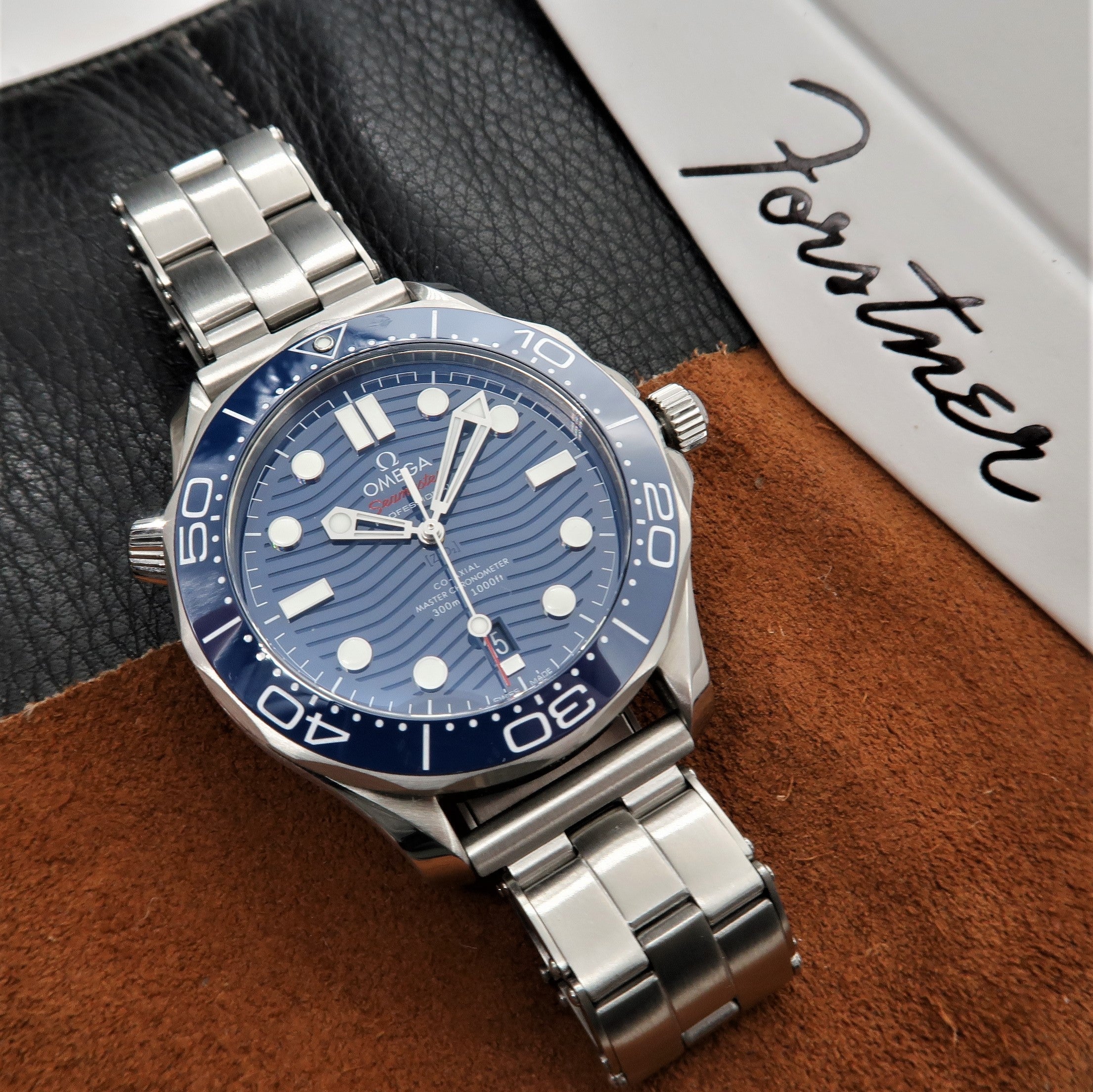 Stainless steel dive watch with blue sunburst dial, applied indices, and matching blue rotating bezel on rivet bracelet