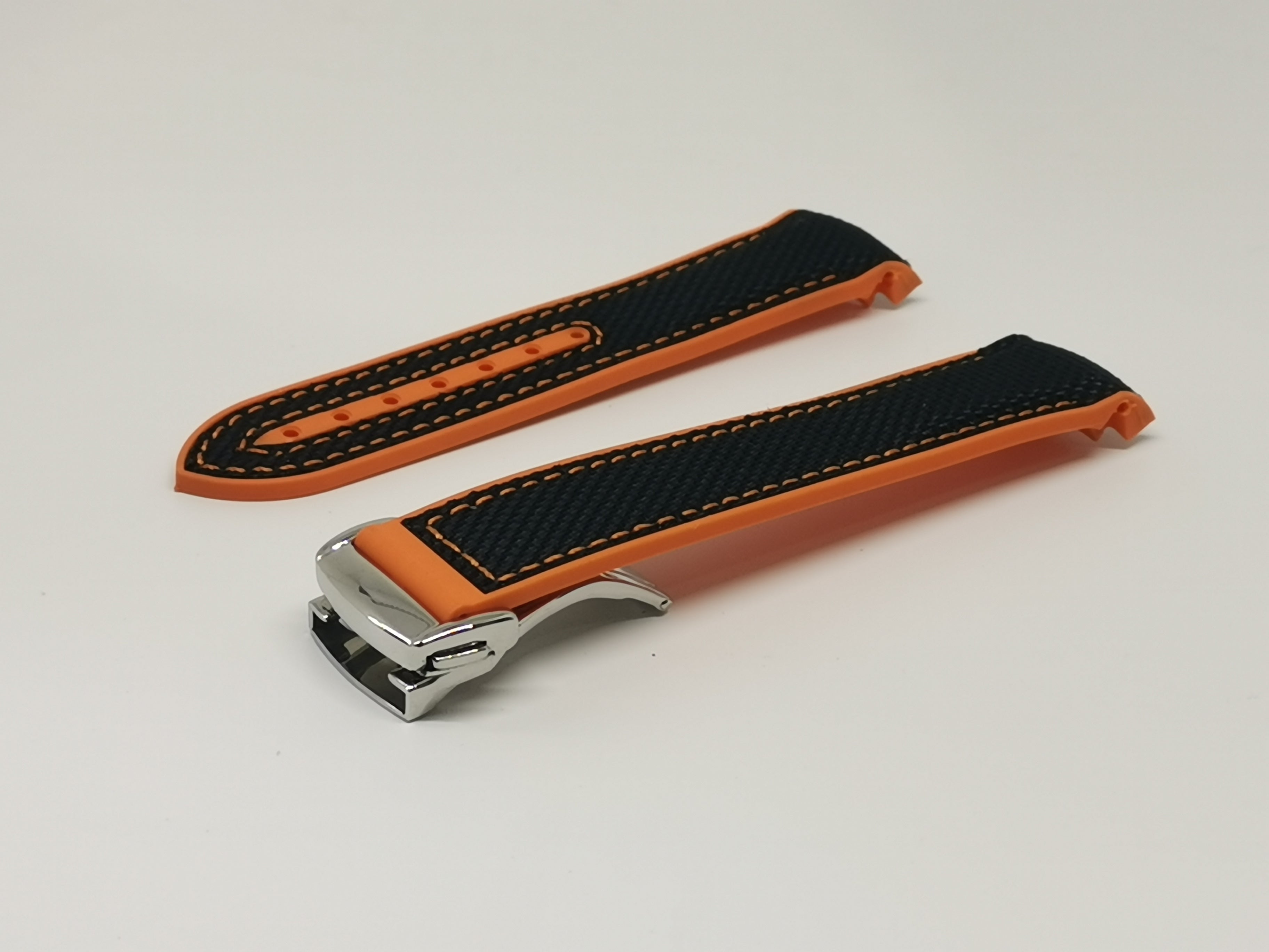 Curved King Hybrid Rubber watch strap in black and orange with white stitching and deployant clasp
