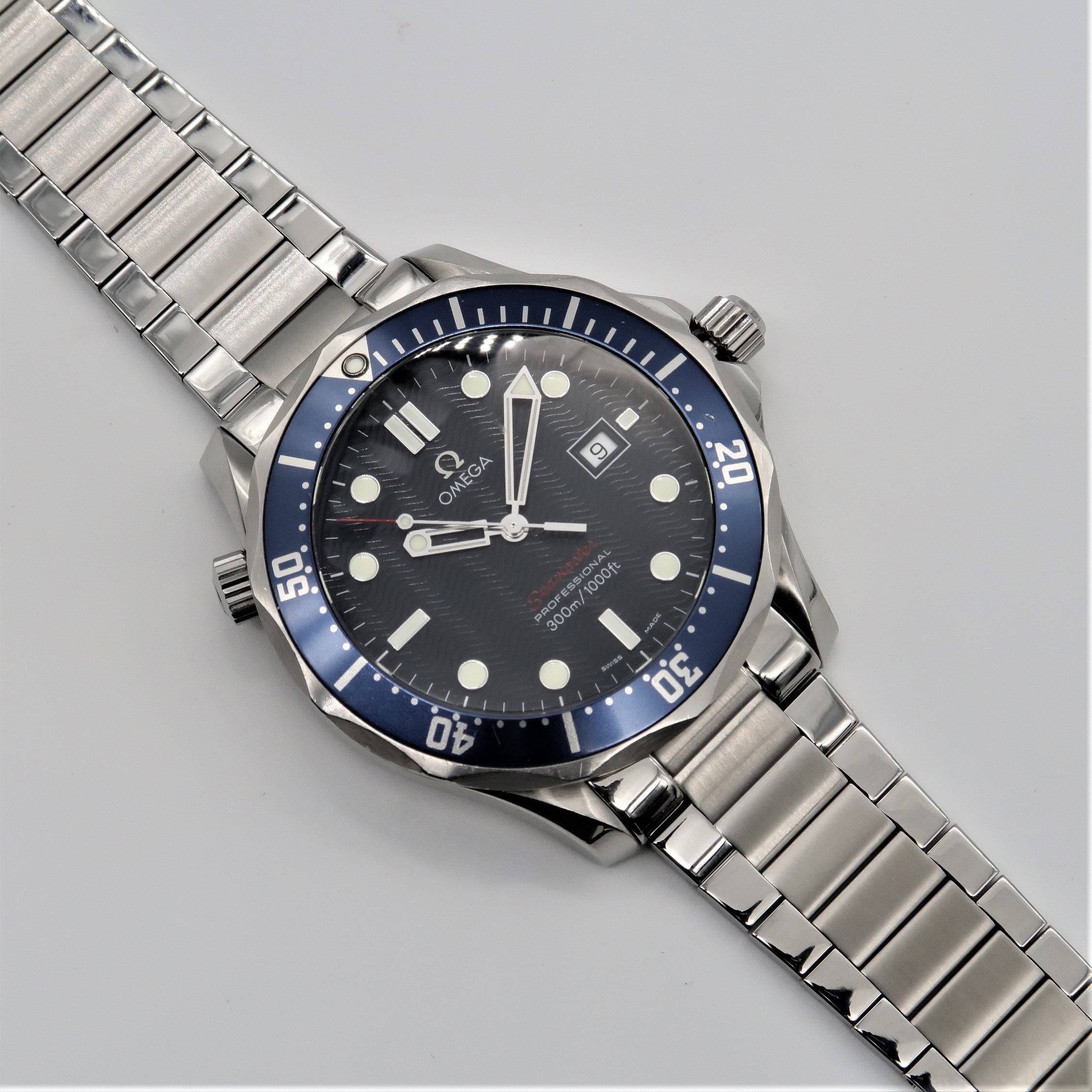 Omega Seamaster dive watch with stainless steel bracelet and blue bezel on white background