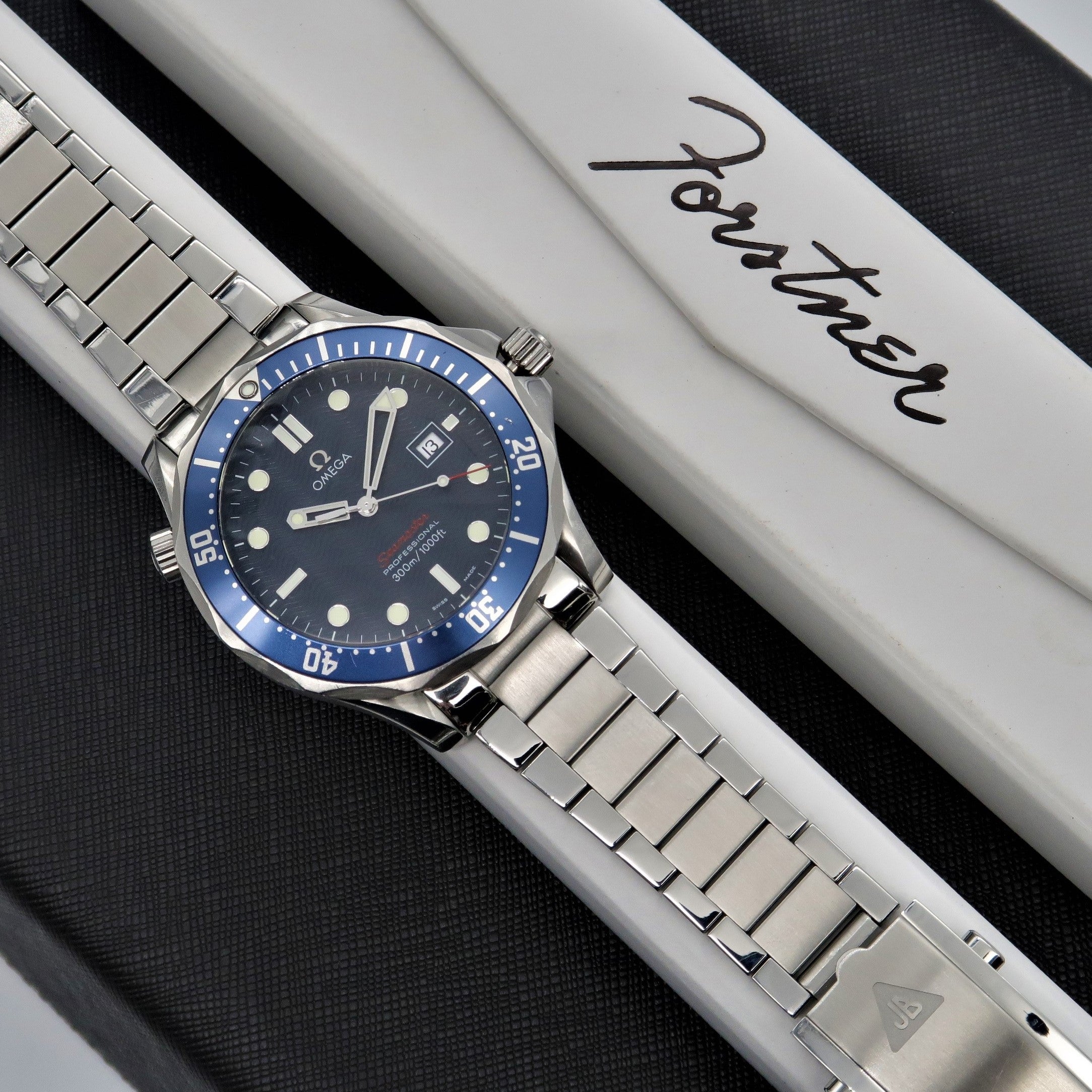Omega Seamaster dive watch with blue bezel and steel bracelet on white branded box