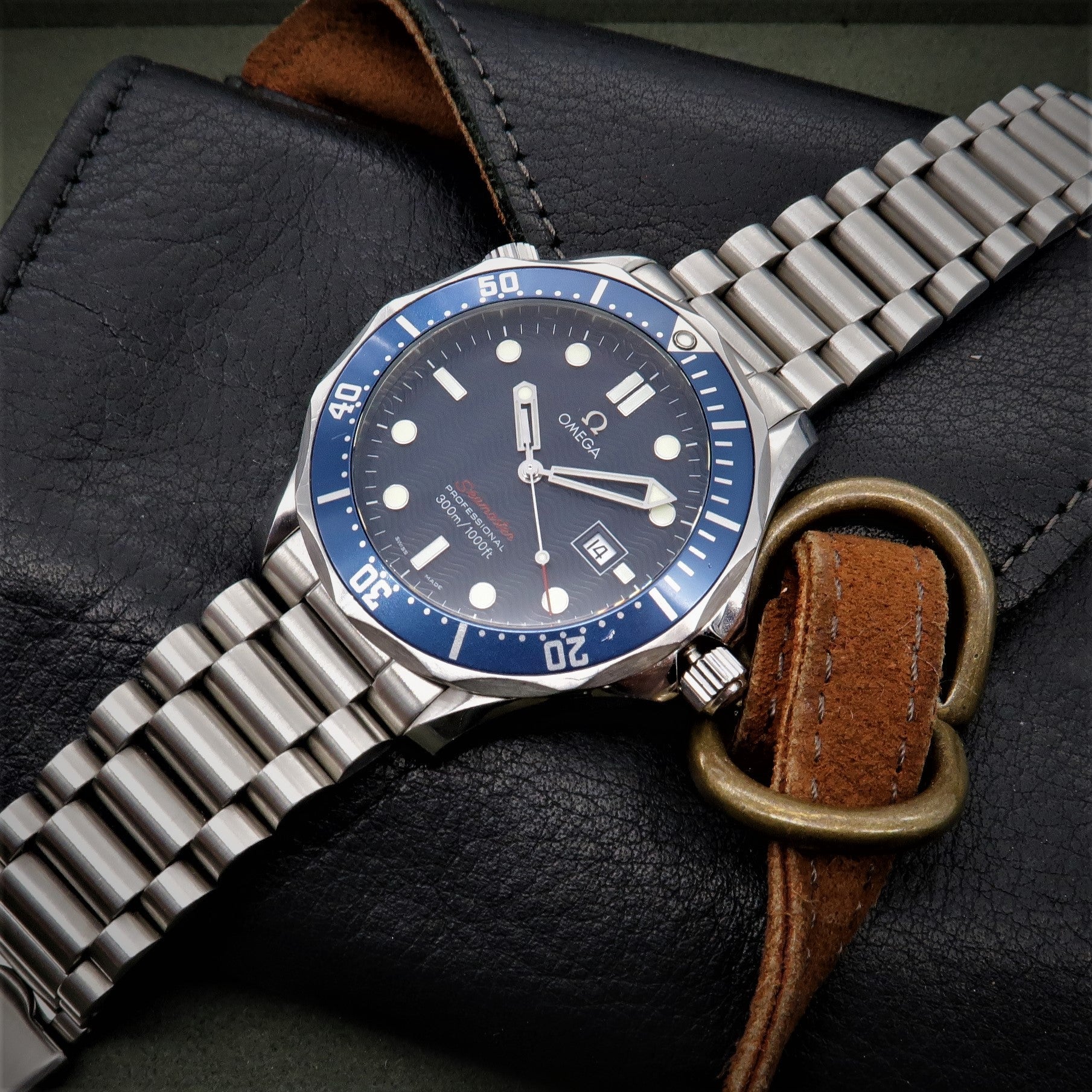 Omega Seamaster dive watch with blue bezel, stainless steel bracelet, and dark dial on black leather strap