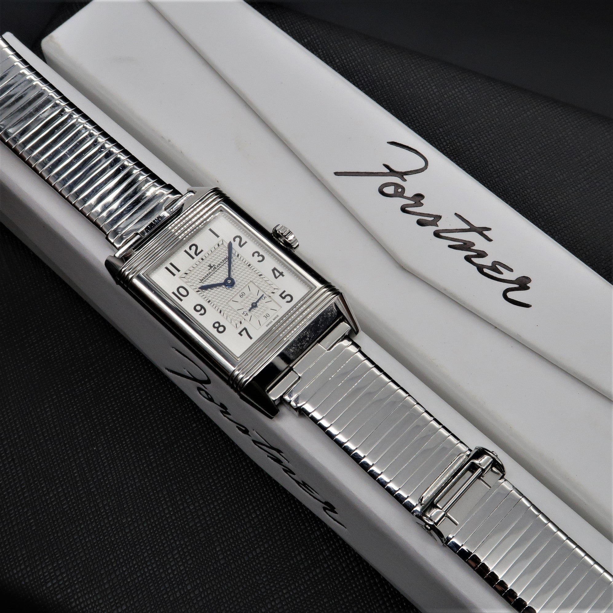 Vintage-style rectangular stainless steel watch with silver metal bracelet, cream dial, and Arabic numerals on white branded box
