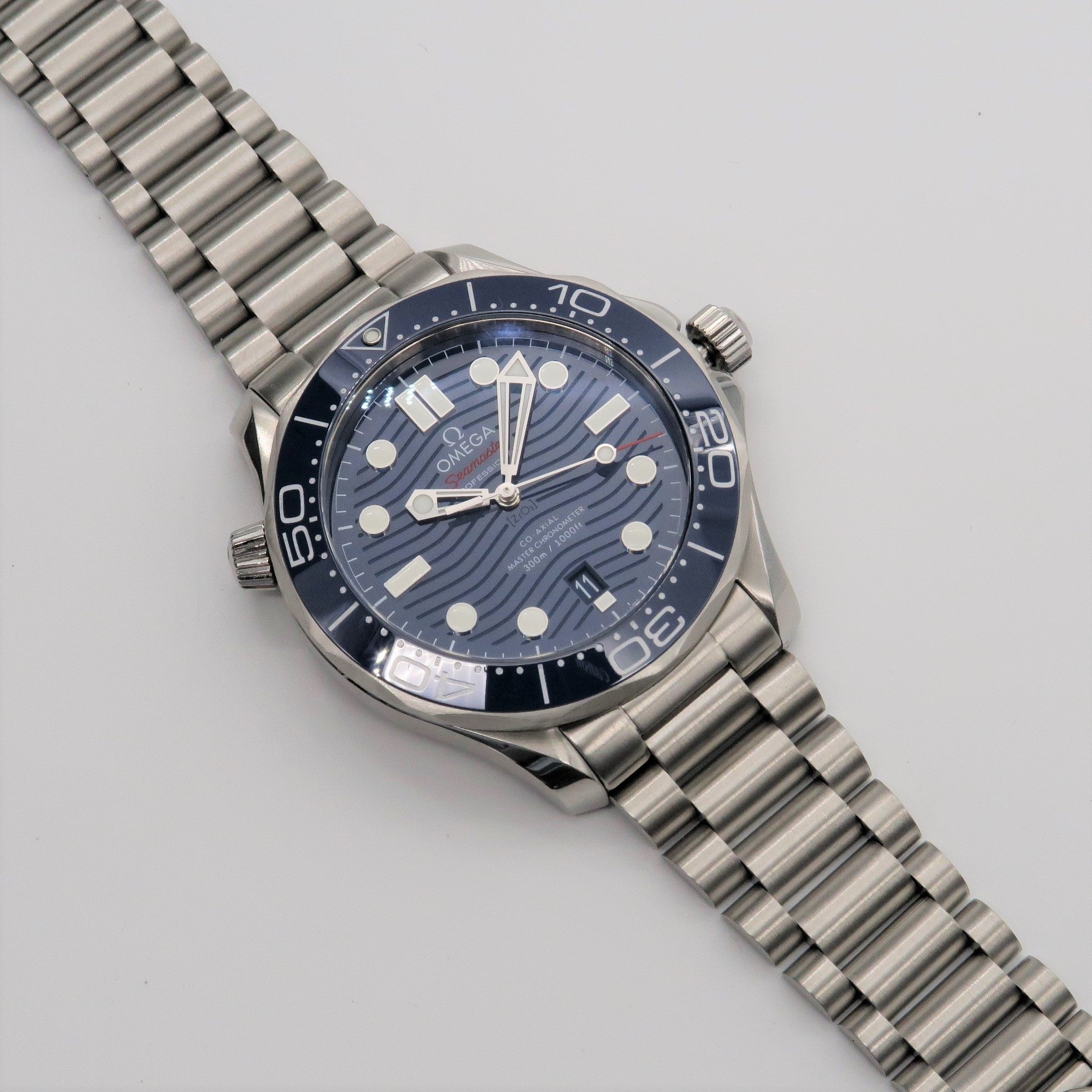 Omega Seamaster dive watch with blue dial, stainless steel bracelet and black bezel on white background