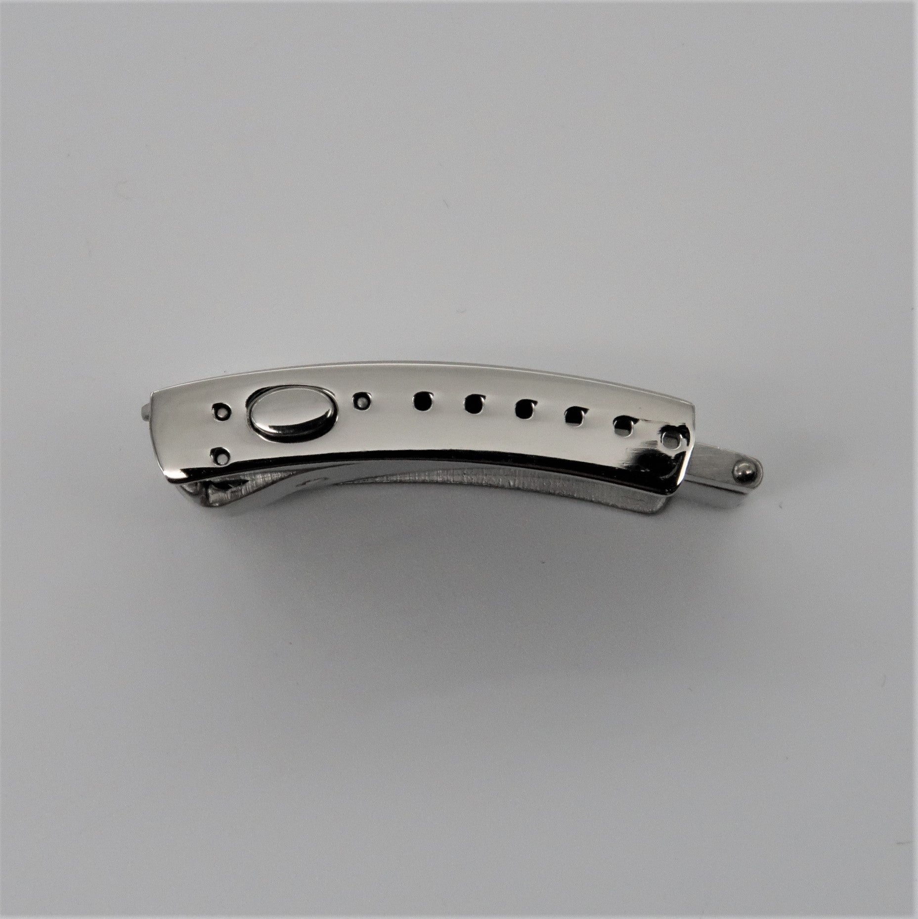 Stainless steel push-button folding knife with milled handle and decorative hole pattern, closed position side view