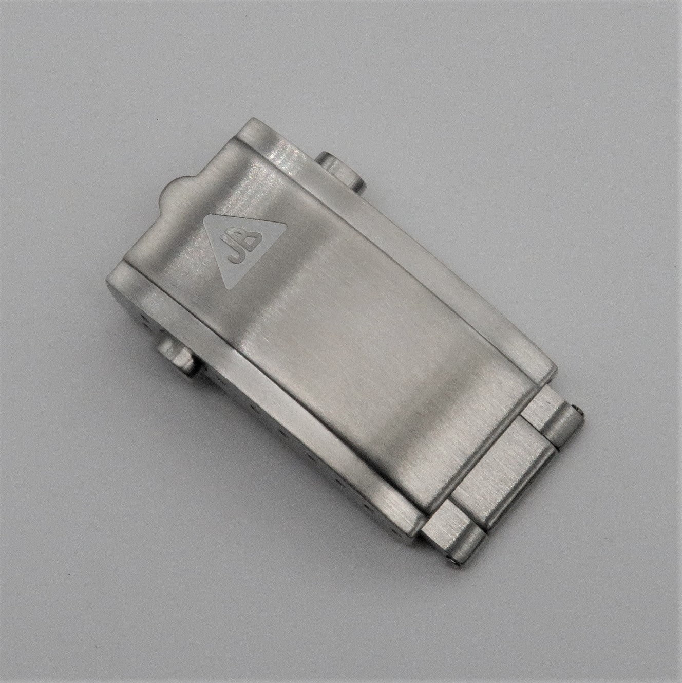 Stainless steel push-button milled clasp with triangular logo, top view on neutral background