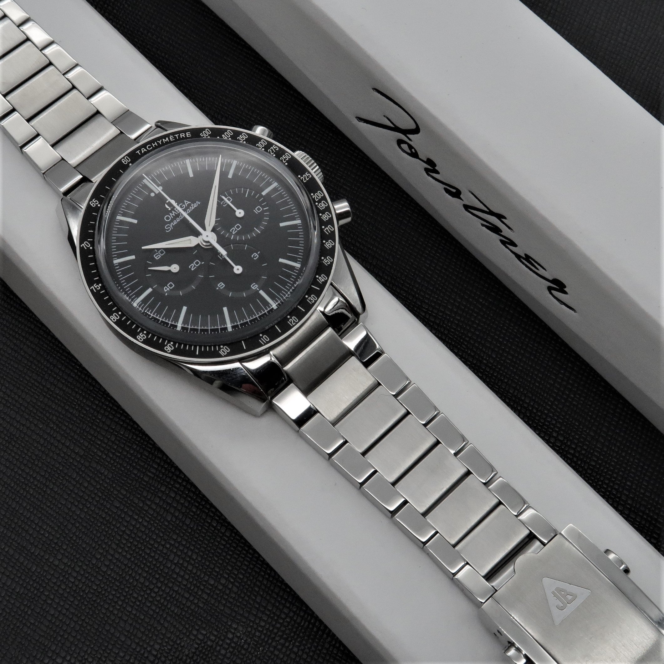 Omega Speedmaster chronograph watch with stainless steel flat link bracelet on white display box